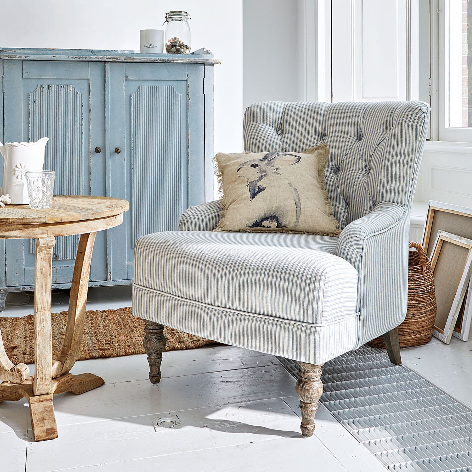 Poltrona a righe con gambe in legno e cuscino con coniglio in interno luminoso e accogliente