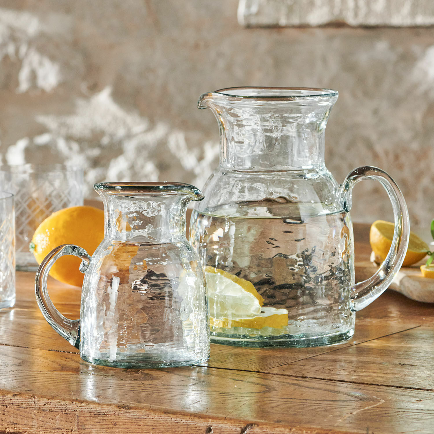 Coppia di caraffe Zamirah Brocche in vetro trasparente con acqua e fette di limone su tavolo in legno rustico