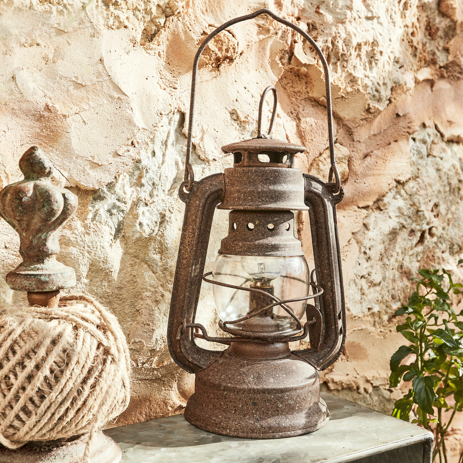 Lanterna a LED Oxcroft Lampada a petrolio in metallo arrugginito stile rustico davanti a muro in pietra, decorazione vintage