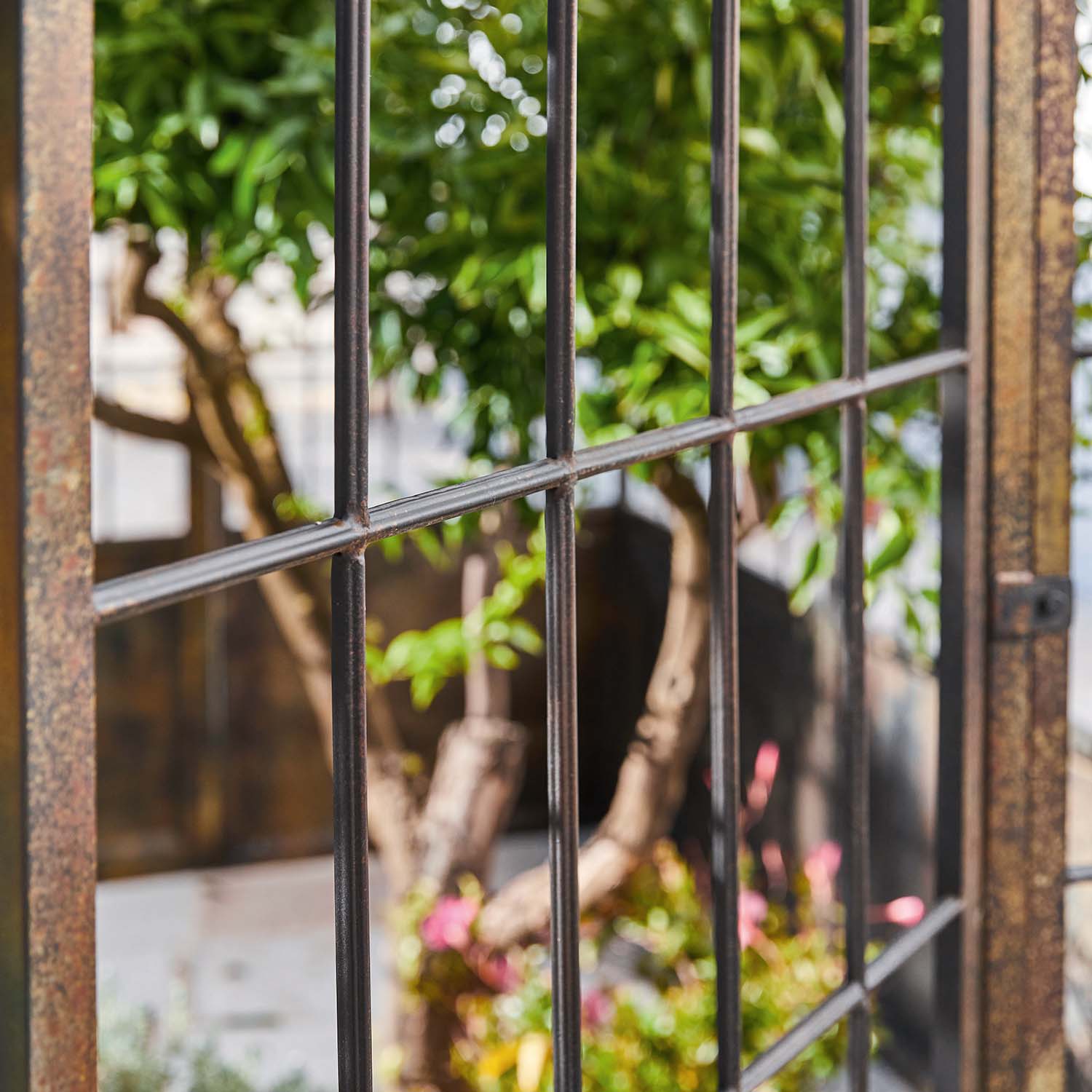 Griglia metallica da giardino con vista su piante verdi e fiori colorati sullo sfondo