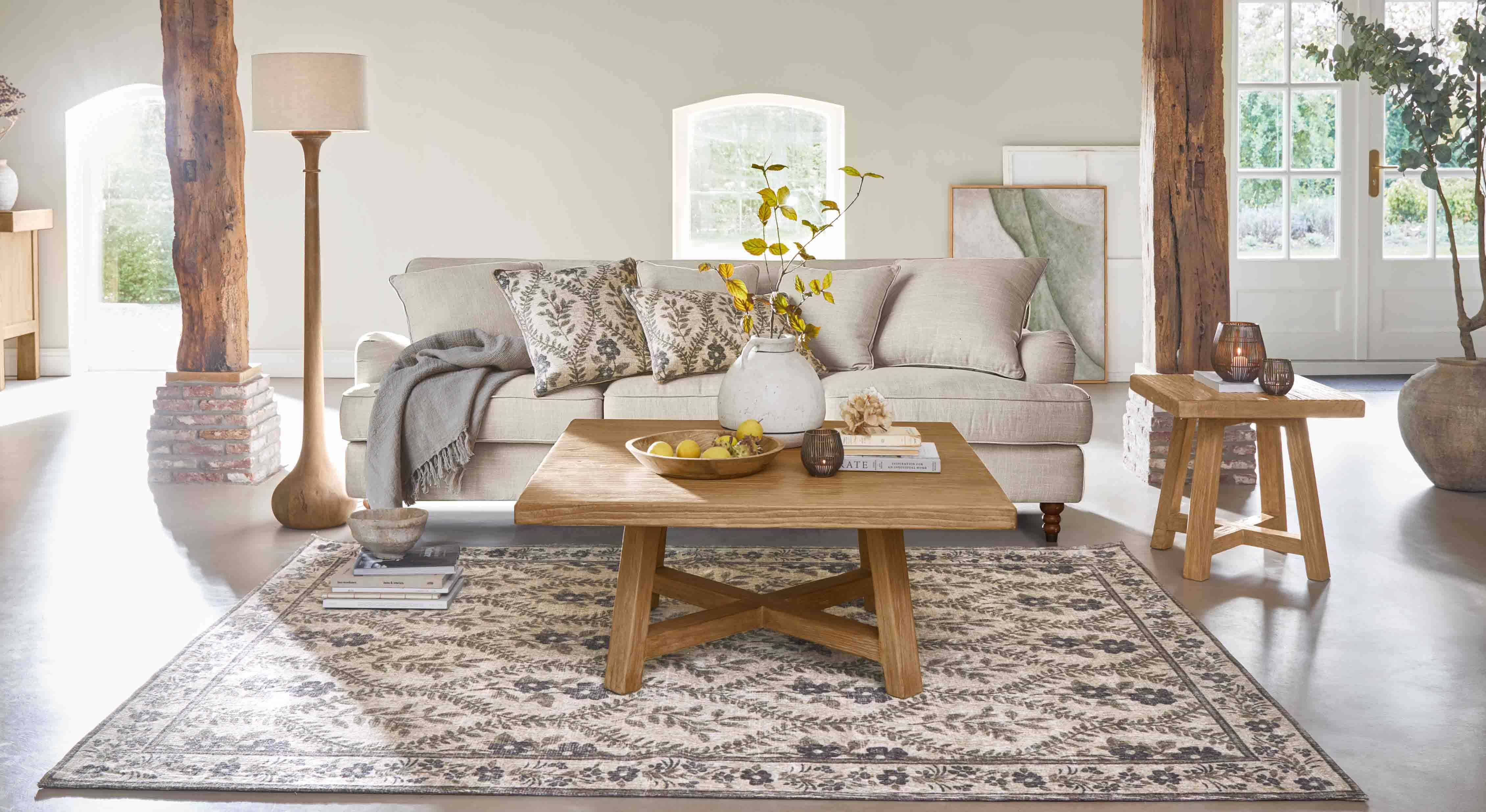 Soggiorno accogliente con divano beige, tavolino in legno e tappeto decorativo a motivo floreale