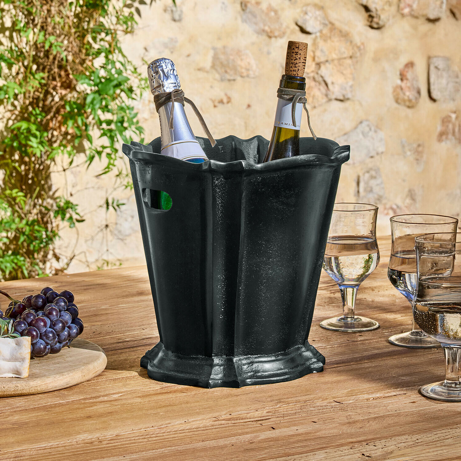 Secchiello del ghiaccio Trévaux Secchiello per ghiaccio in metallo nero con due bottiglie di vino su tavolo in legno all'aperto