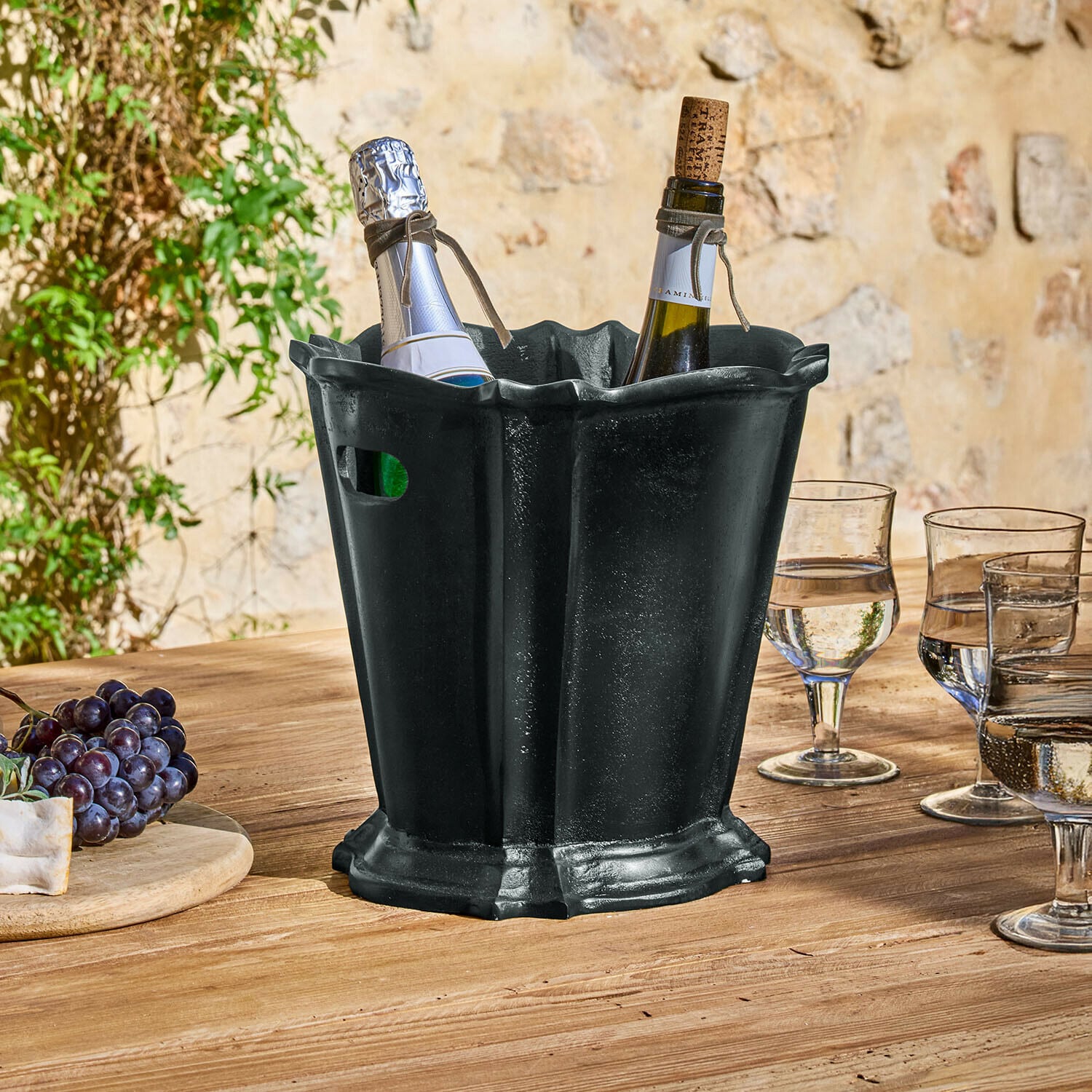 Secchiello del ghiaccio Trévaux Secchiello per ghiaccio in metallo nero con due bottiglie di vino su tavolo in legno all'aperto