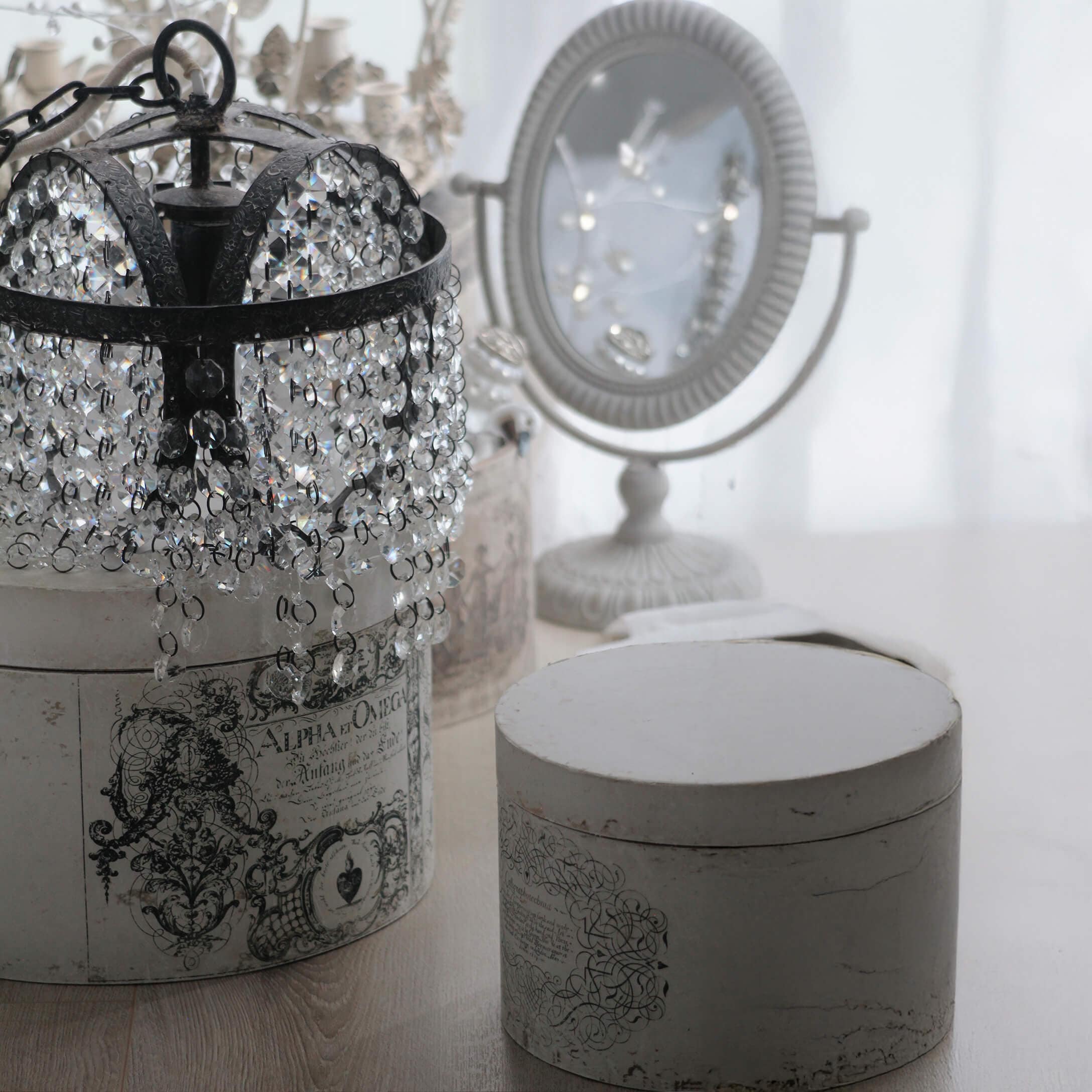 Lampadario in cristallo con struttura in metallo nero su scatola vintage bianca decorata