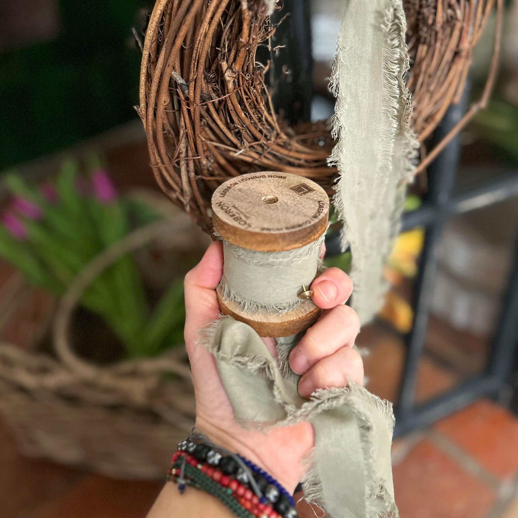 Nastro grigio in cotone con bordi sfrangiati su rocchetto di legno per decorazioni e fai-da-te