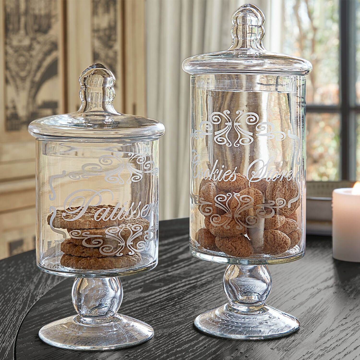 Coppia di barattoli Suzie Barattoli di vetro con coperchi e scritte decorative pieni di biscotti su tavolo nero