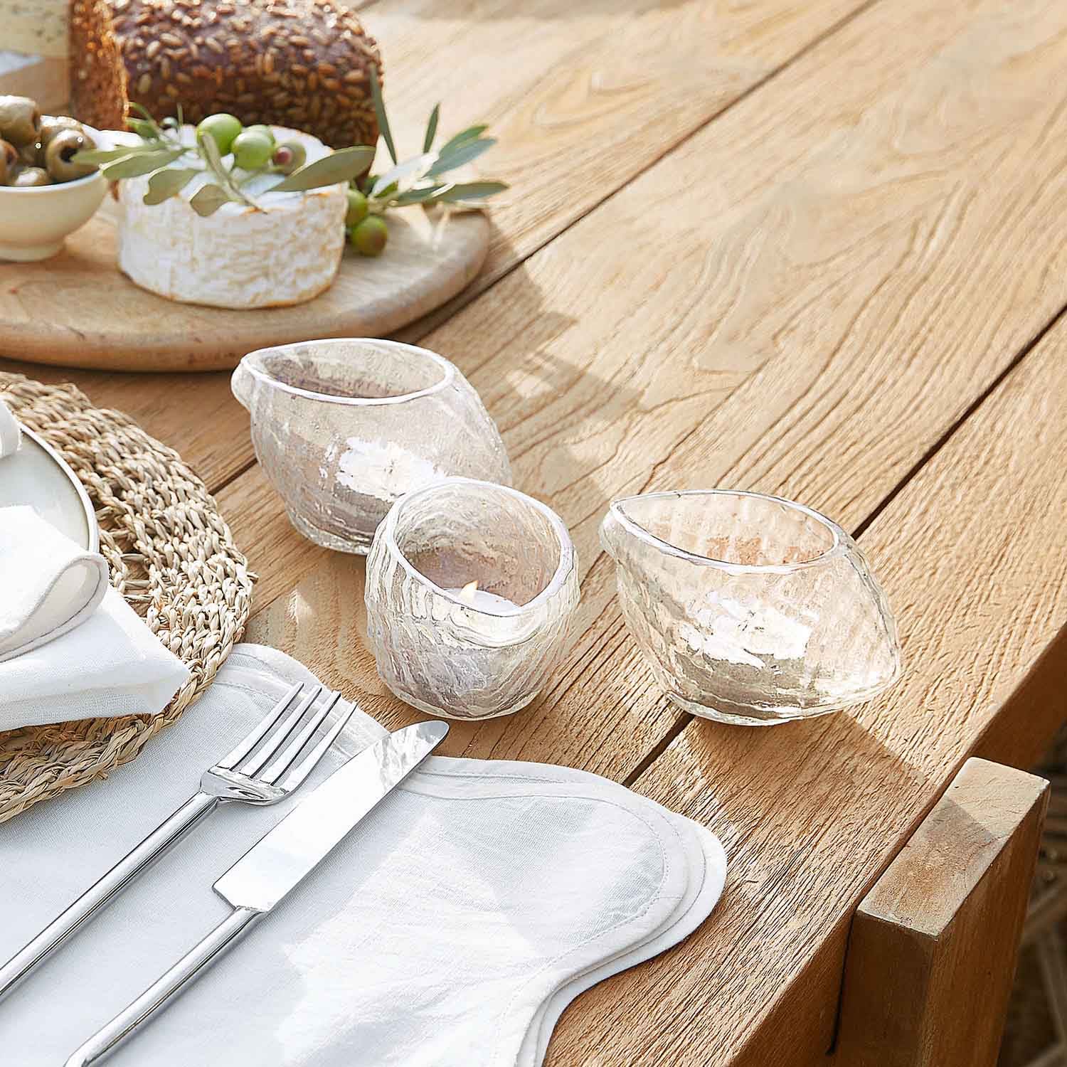 Set di tre portacandele in vetro trasparente con forma irregolare su tavolo in legno chiaro