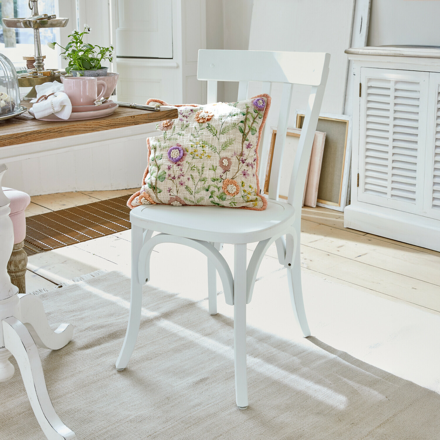 Sedia Passigny Sedia in legno bianco con cuscino ricamato a fiori in una luminosa sala da pranzo
