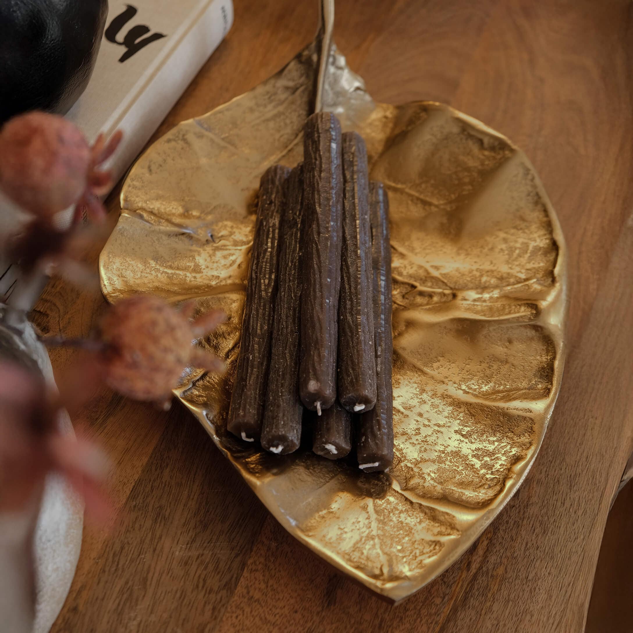 Vassoio in metallo dorato a forma di foglia con candele decorative marroni su tavolo in legno
