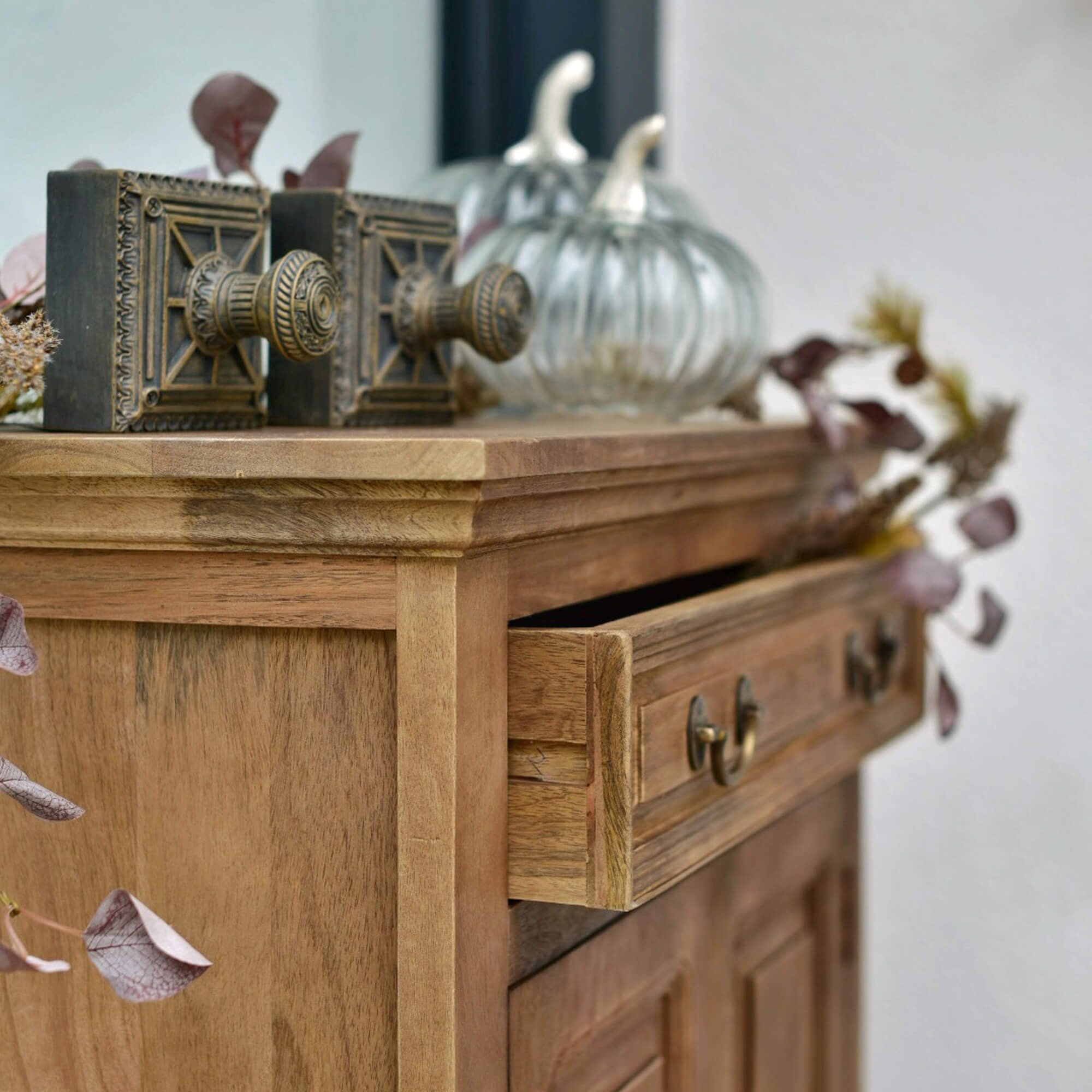 Comò in legno con cassetto aperto, maniglie decorative in ottone e decorazioni in vetro a forma di zucca