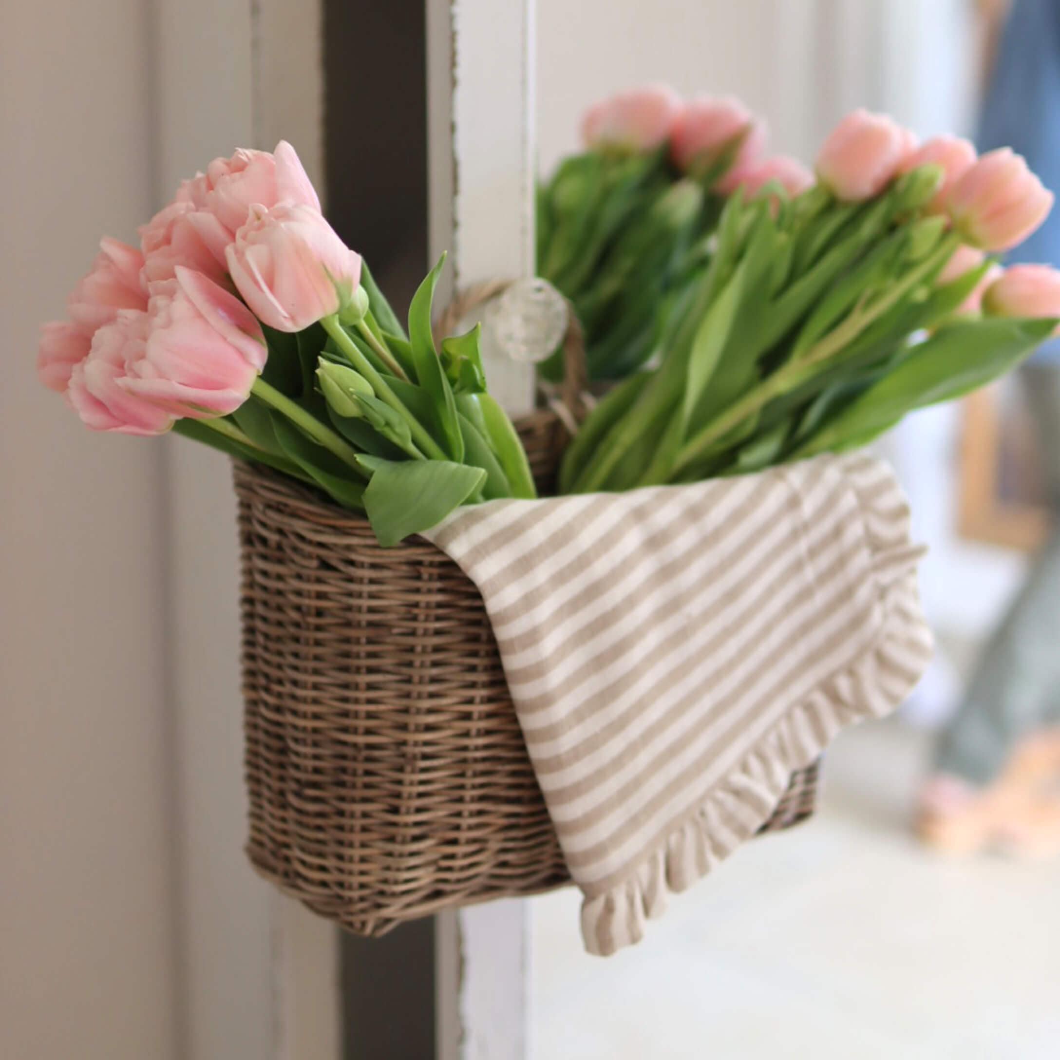 Cesto in vimini con tulipani rosa e strofinaccio di cotone a righe per decorazione casa