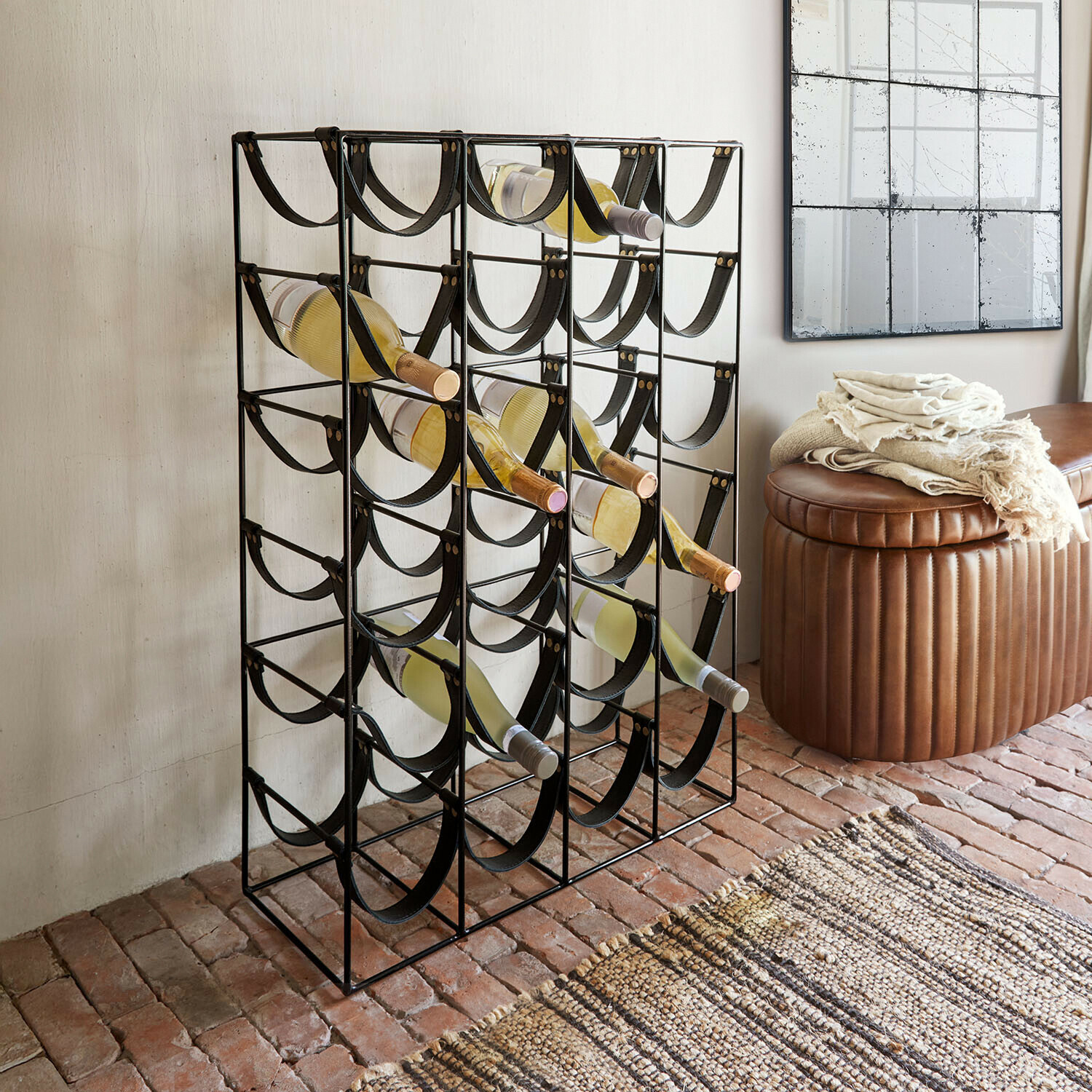 Scaffale per vino Vareesh Portabottiglie in metallo nero con cinghie nere, contiene bottiglie di vino bianco nel soggiorno.