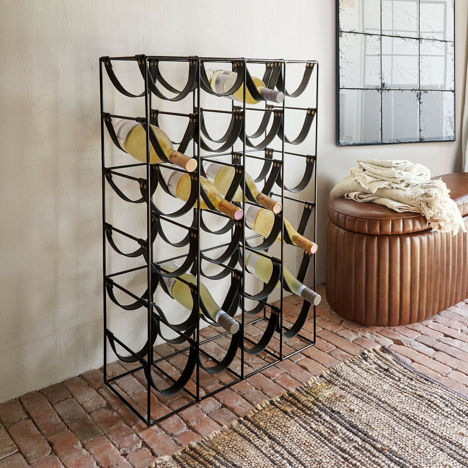 Scaffale per vino Vareesh Portabottiglie in metallo nero con cinghie nere, contiene bottiglie di vino bianco nel soggiorno.