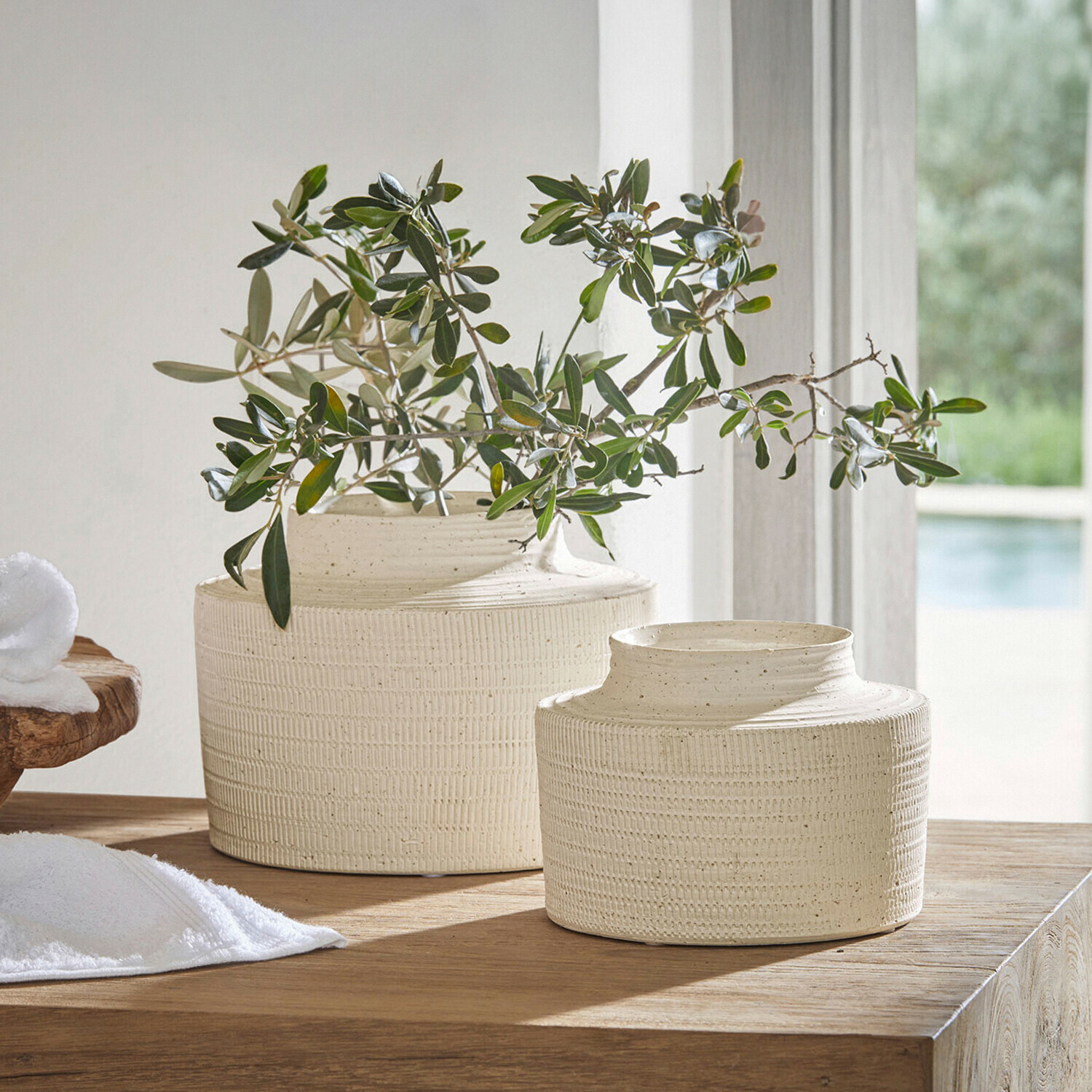 Coppia di vasi Délavrie Due vasi in ceramica crema con texture su tavolo in legno con rami verdi