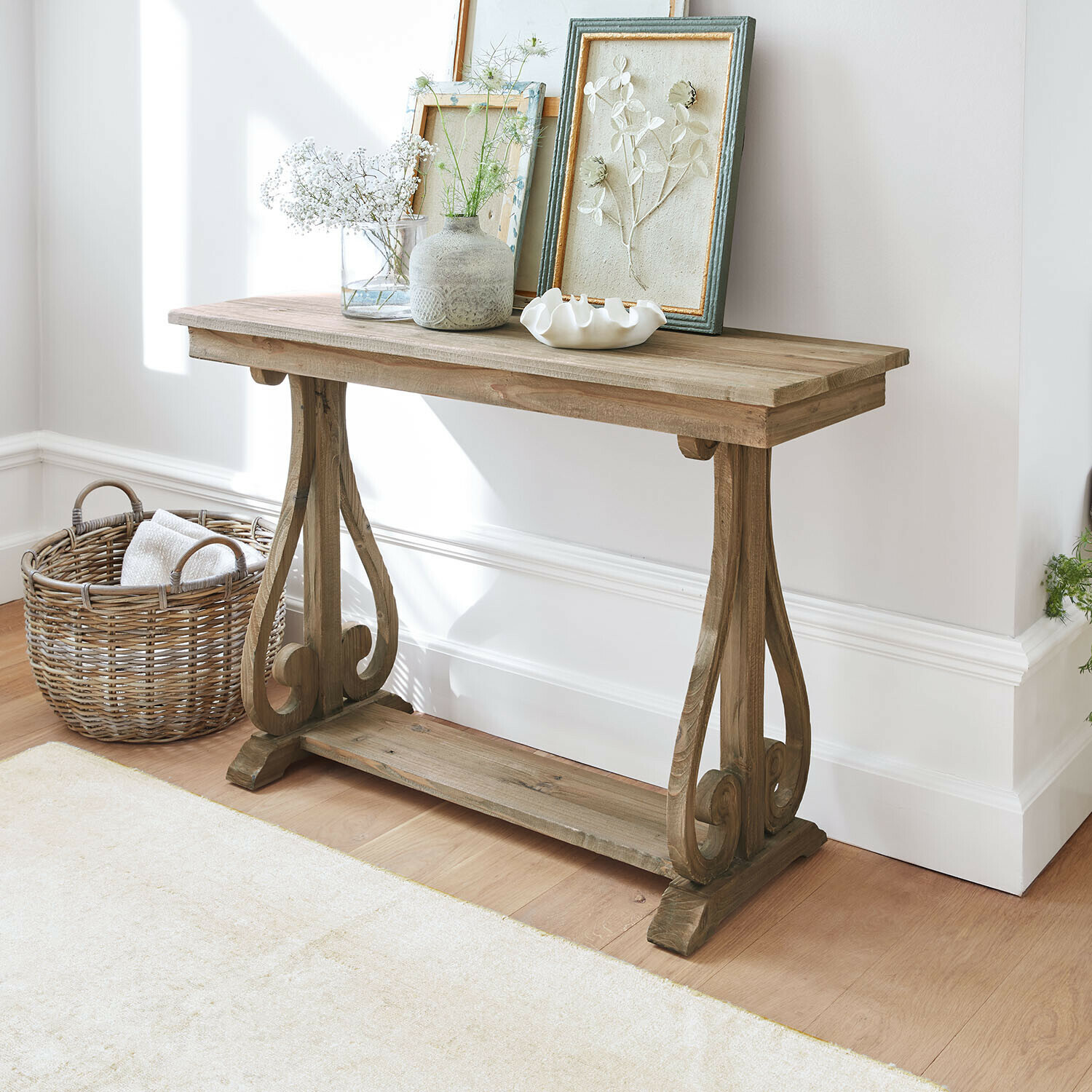 Consolle Chavignac Consolle in legno naturale con cornici decorative e vasi in ambiente luminoso