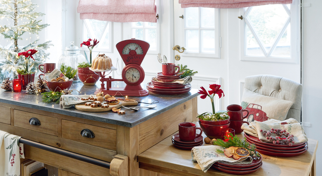 Cucina natalizia con stoviglie rosse in ceramica e decorazioni su piano di legno