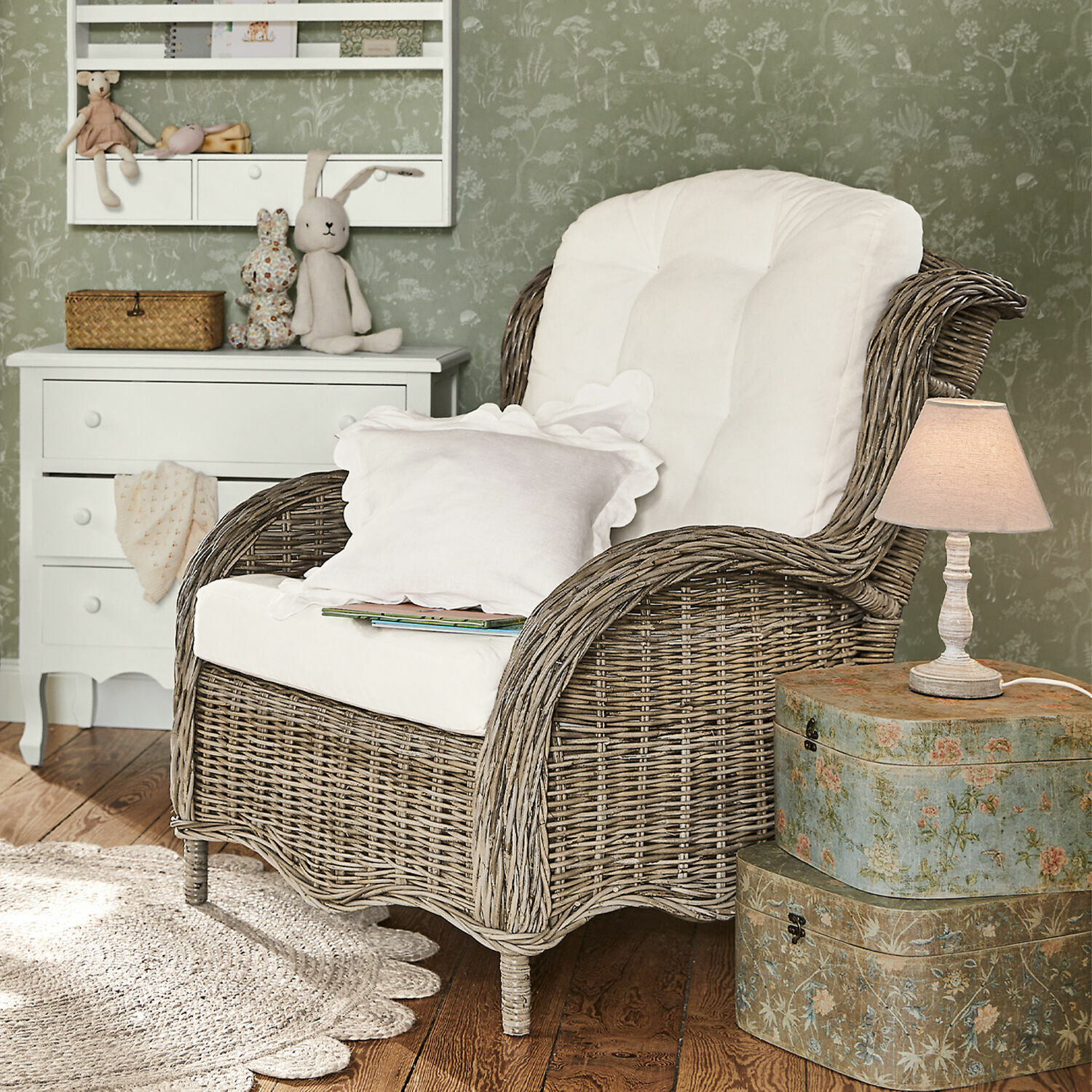 Poltrona Hailee Poltrona in vimini con cuscino bianco in ambiente accogliente con lampada e cassettiera