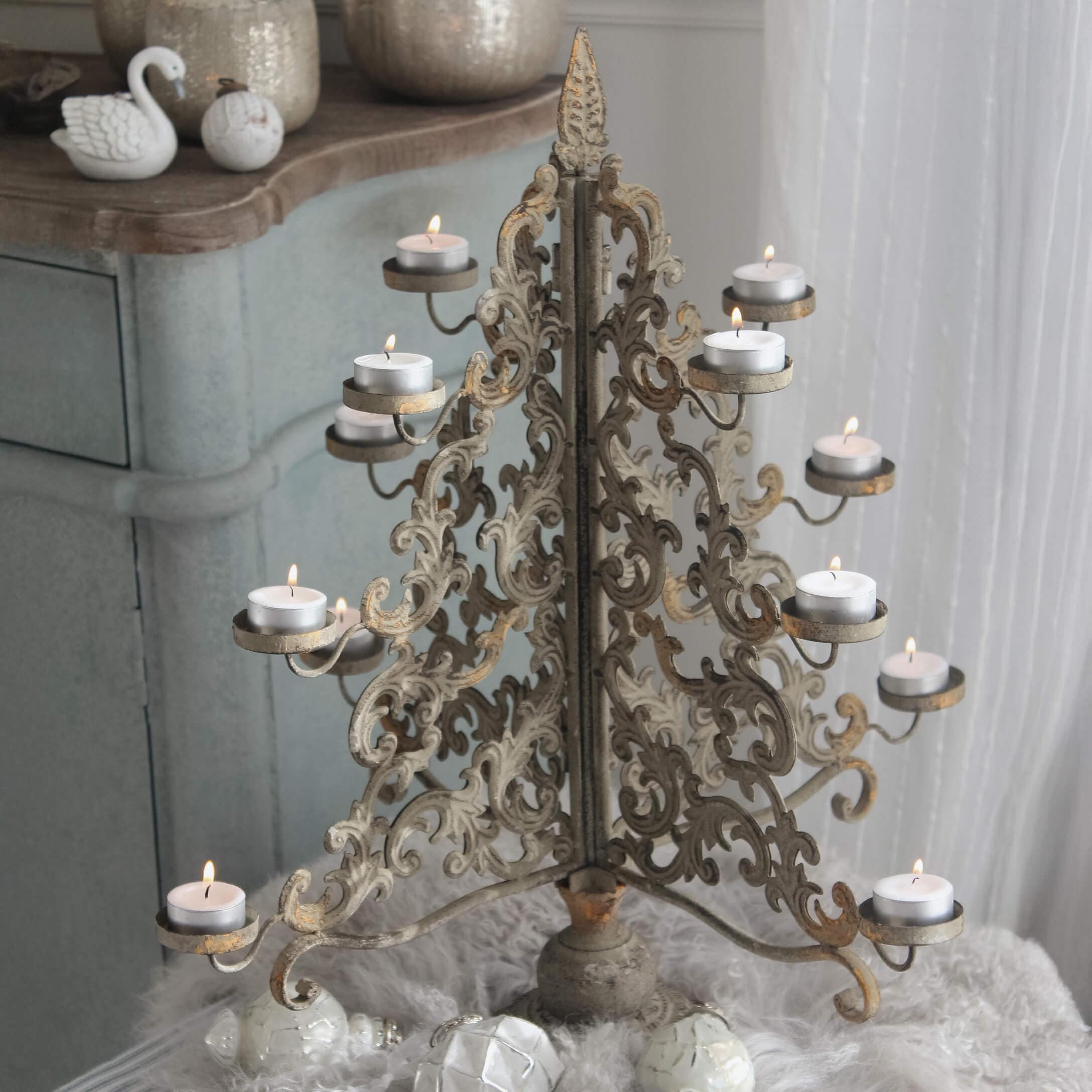 Portacandele in metallo dorato anticato con motivo traforato e candele tealight accese
