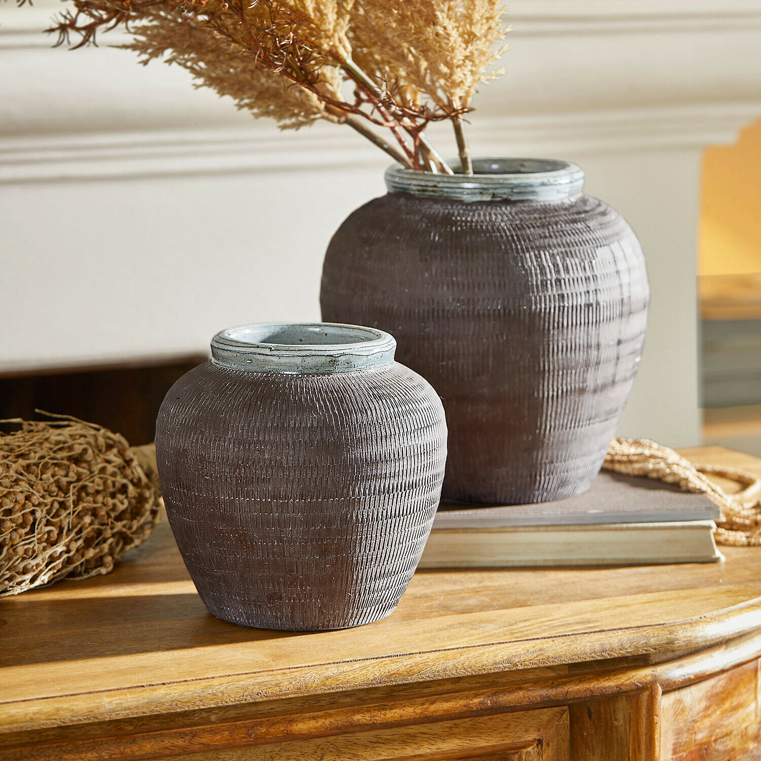 Coppia di vasi Calverna Due vasi decorativi in ceramica marrone su tavolo in legno con piante essiccate