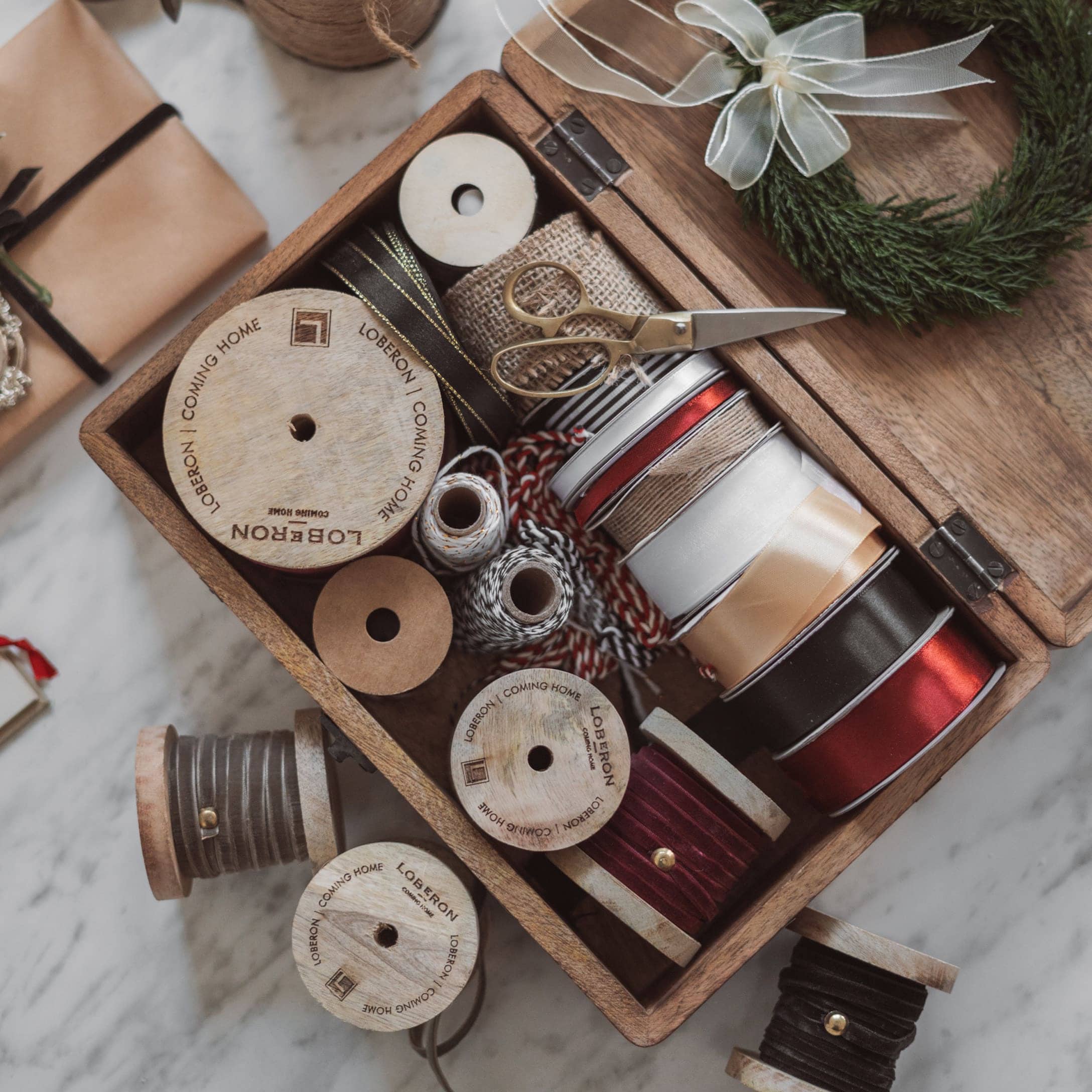 Bobine di legno con nastri vari e forbici in scatola per decorazioni e confezioni regalo