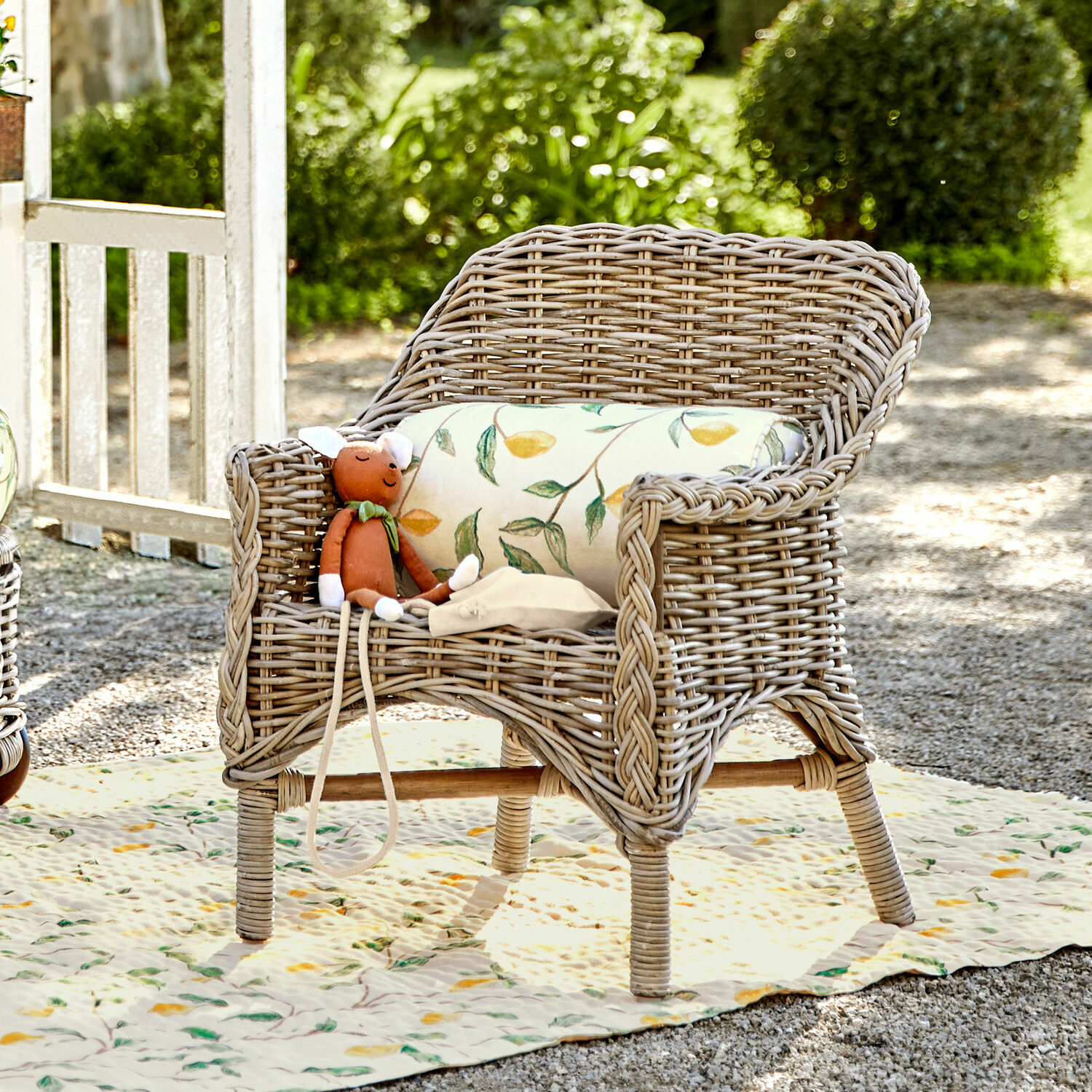 Sedia per bambini Narivena Poltrona in rattan colore naturale con cuscino a foglie e peluche in giardino soleggiato