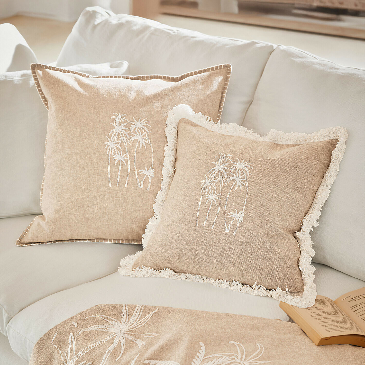 Coppia di copricuscini Windlake Cuscini beige in lino con ricamo bianco di palme su divano chiaro, tessuti decorativi per soggiorno