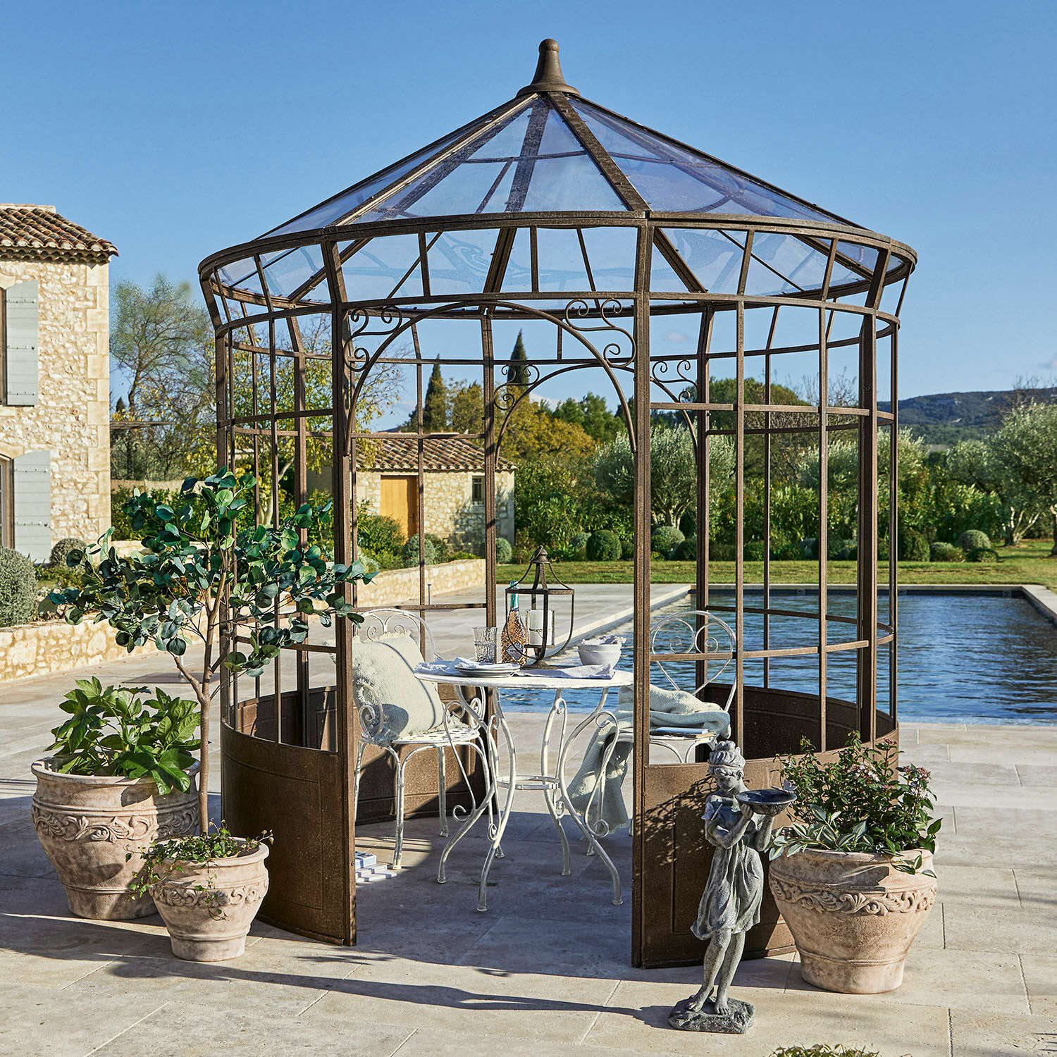 Gazebo Murillo Gazebo da giardino decorativo in metallo color ruggine con tavolo bianco e sedie su terrazza vicino piscina