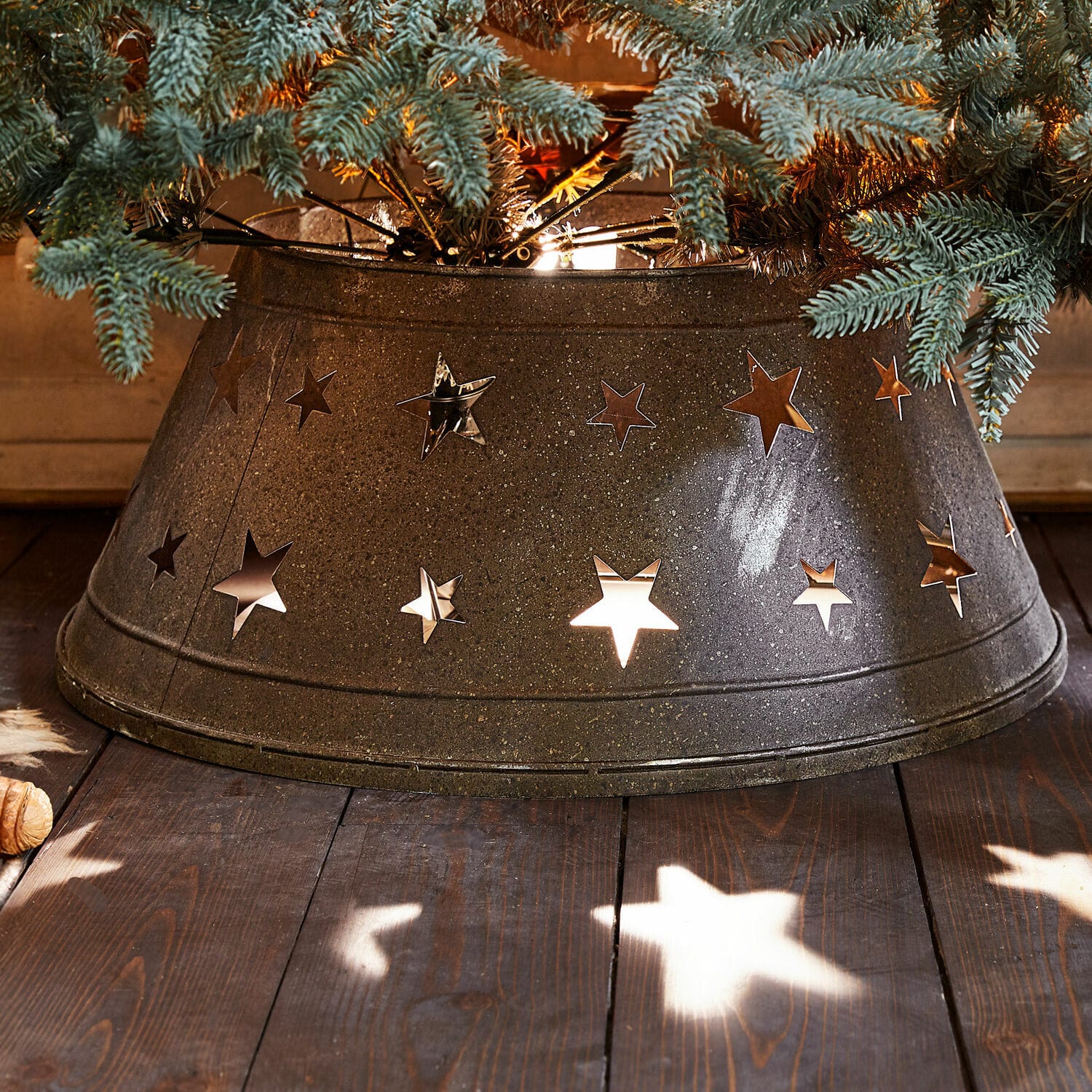 Copri base per albero di Natale Ysabelle Base in metallo per albero di Natale con ritagli a forma di stella, decorazione natalizia grigio scuro su pavimento in legno
