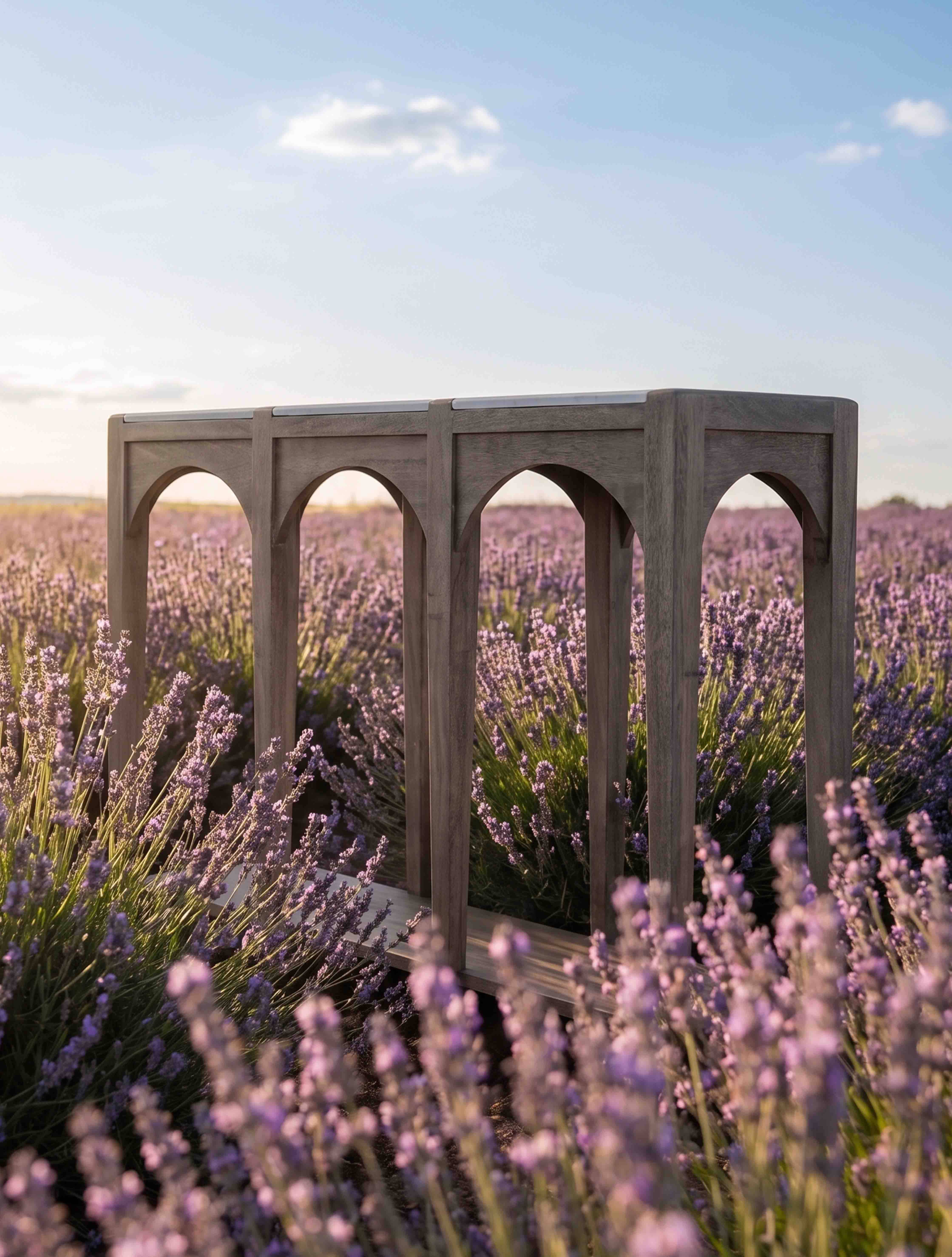 Tavolo da giardino in legno grigio con gambe ad arco su sfondo di campo di lavanda viola
