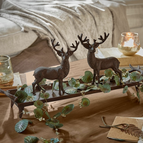 Decorazione con due cervi in metallo marrone su base in legno con foglie verdi su tavolo