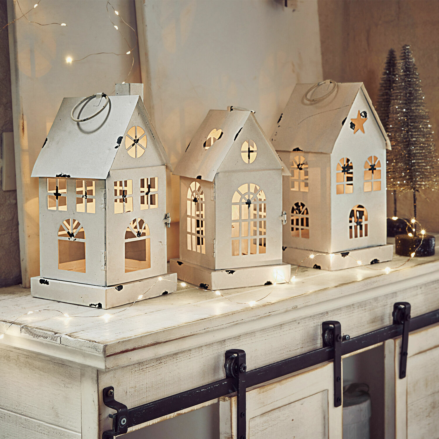 Set di 3 lanterne a LED Village Set di tre lanterne in metallo bianco a forma di casetta con finestre ritagliate e illuminazione festiva