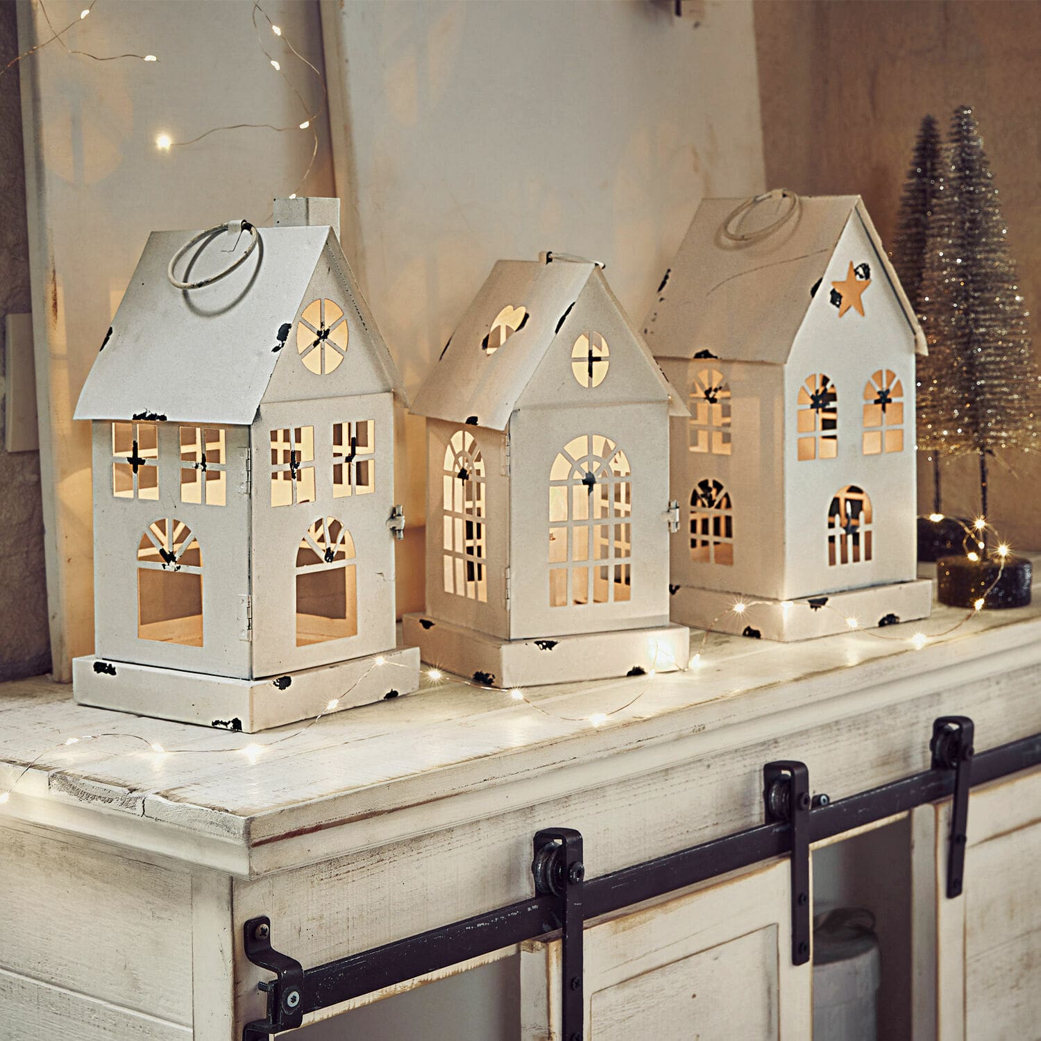Set di 3 lanterne a LED Village Set di tre lanterne in metallo bianco a forma di casetta con finestre ritagliate e illuminazione festiva