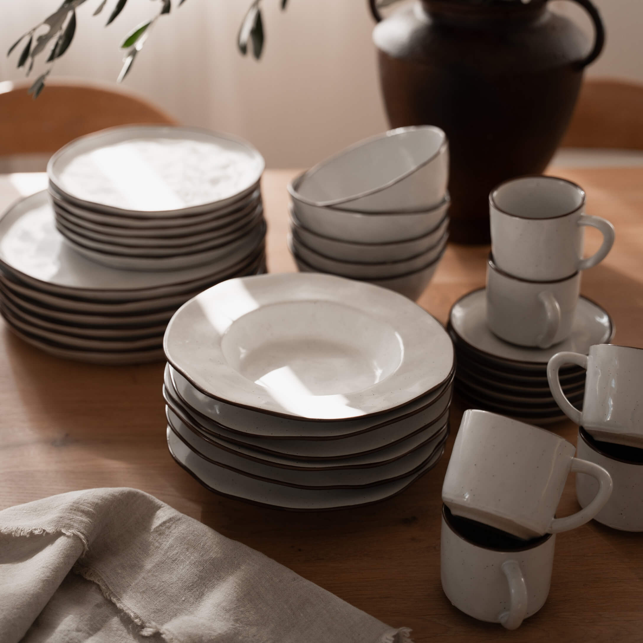 Set di stoviglie in ceramica bianca con bordo marrone su tavolo in legno, utensili da cucina