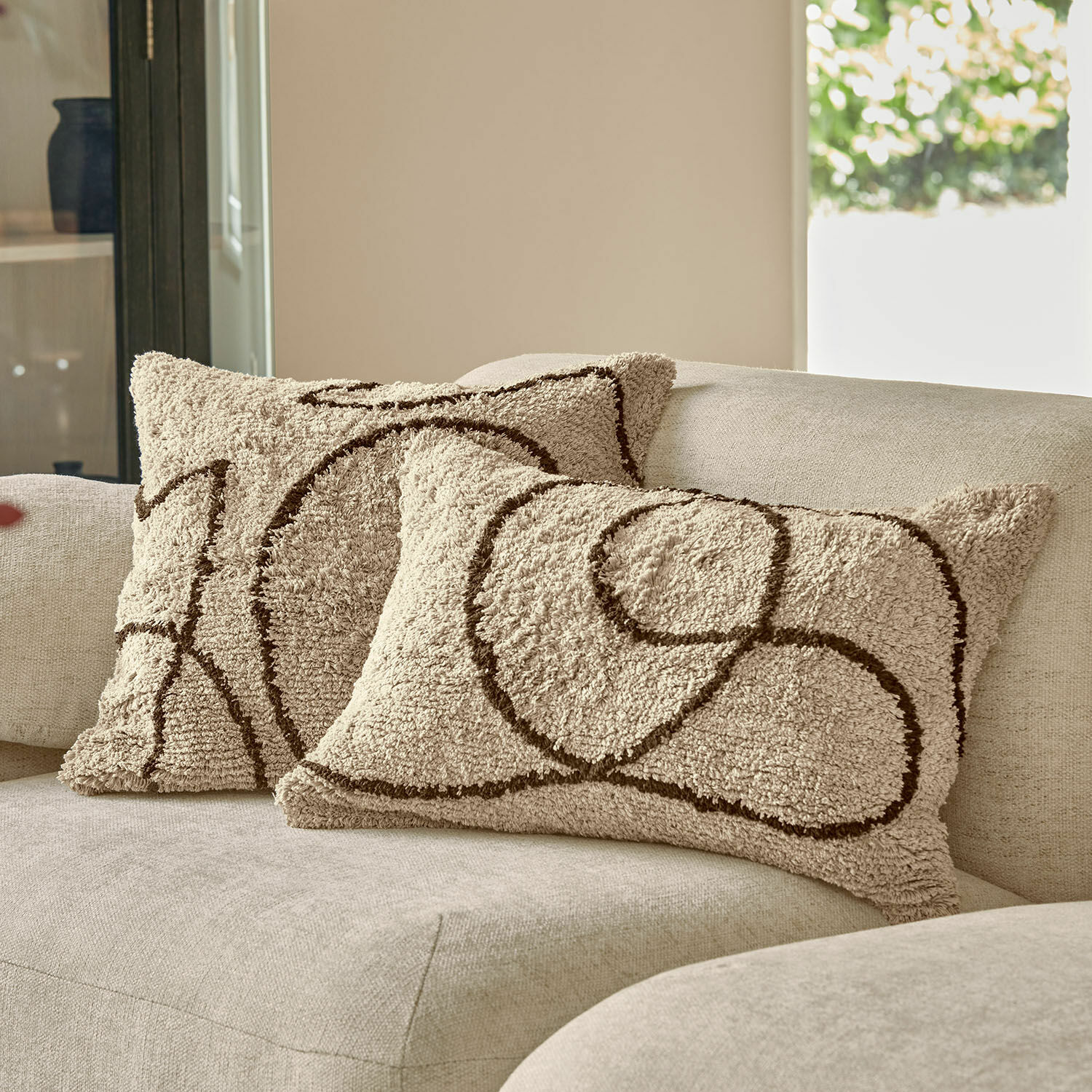 Coppia di copricuscini Lavinois Cuscini decorativi beige in materiale morbido con motivo geometrico marrone su divano chiaro