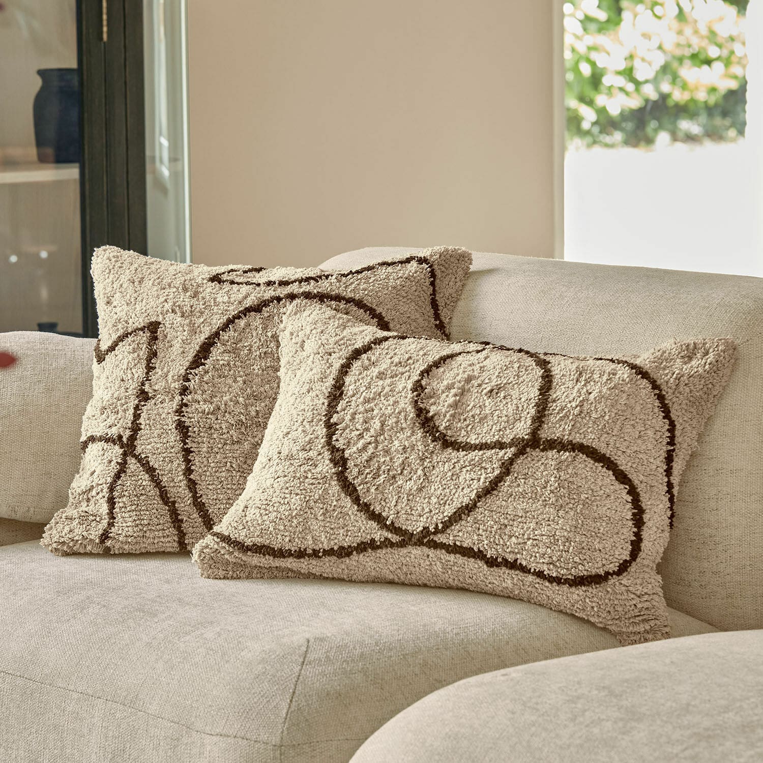 Coppia di copricuscini Lavinois Cuscini decorativi beige in materiale morbido con motivo geometrico marrone su divano chiaro