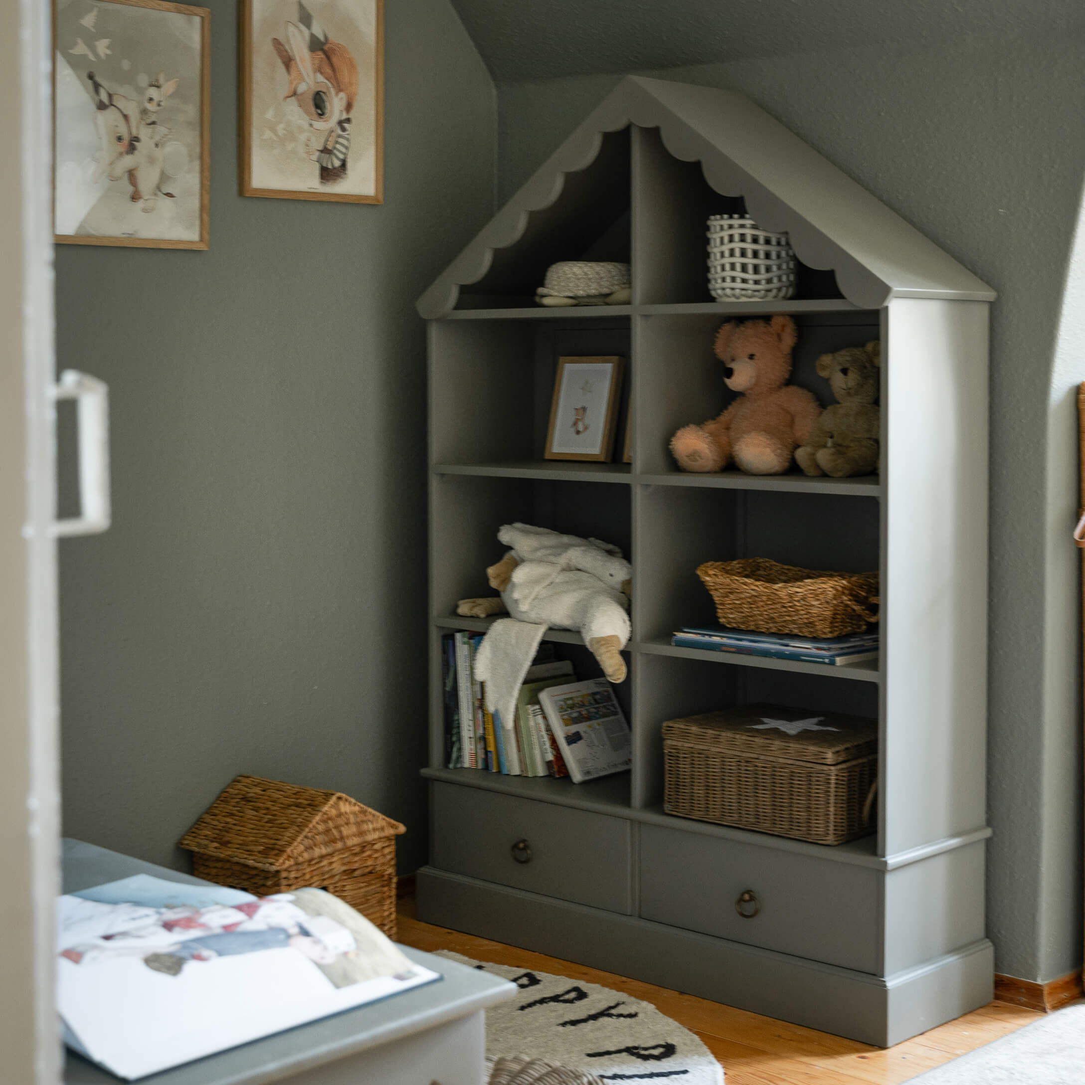 Scaffale grigio in legno a forma di casetta con peluche e cesti portaoggetti in camera bambini