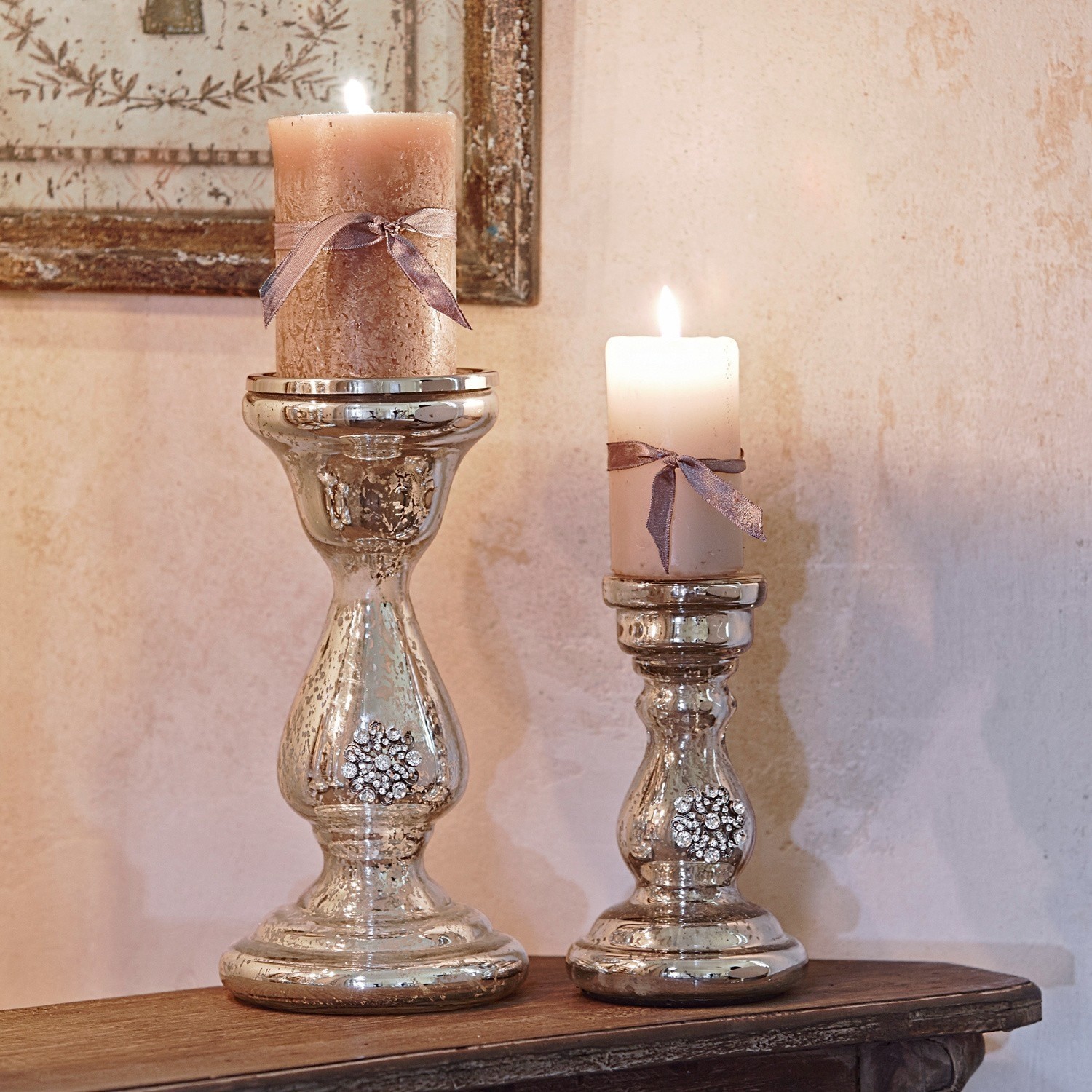 Coppia di portacandele Lysiane Due candelabri argentati con cristalli decorativi e candele beige con fiocchi su tavolo in legno