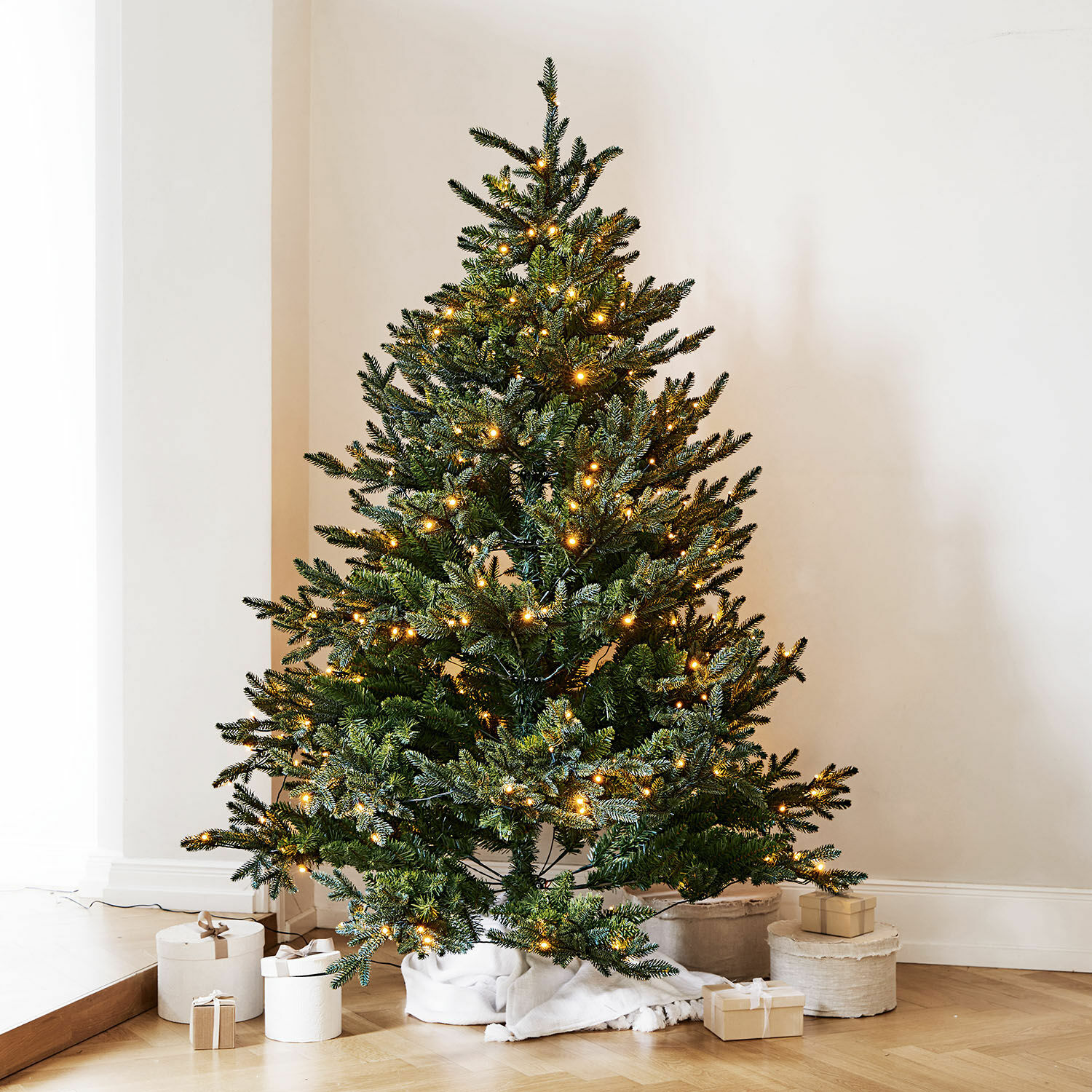 Albero di Natale Franck Albero di Natale artificiale verde con luci LED calde su pavimento in legno con regali
