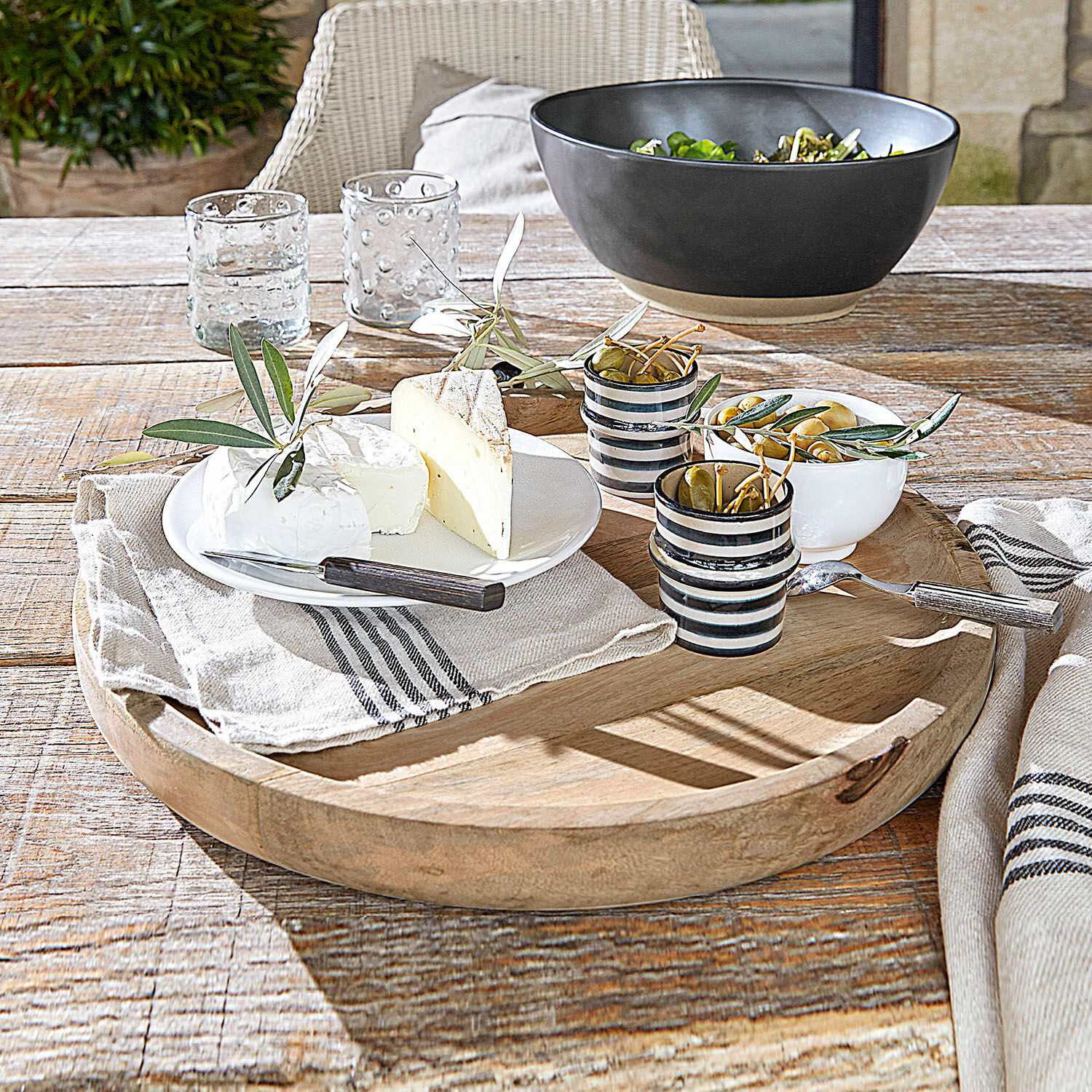 Vassoio Helier Vassoio in legno con formaggi, olive e tazze in ceramica su tavolo rustico in legno