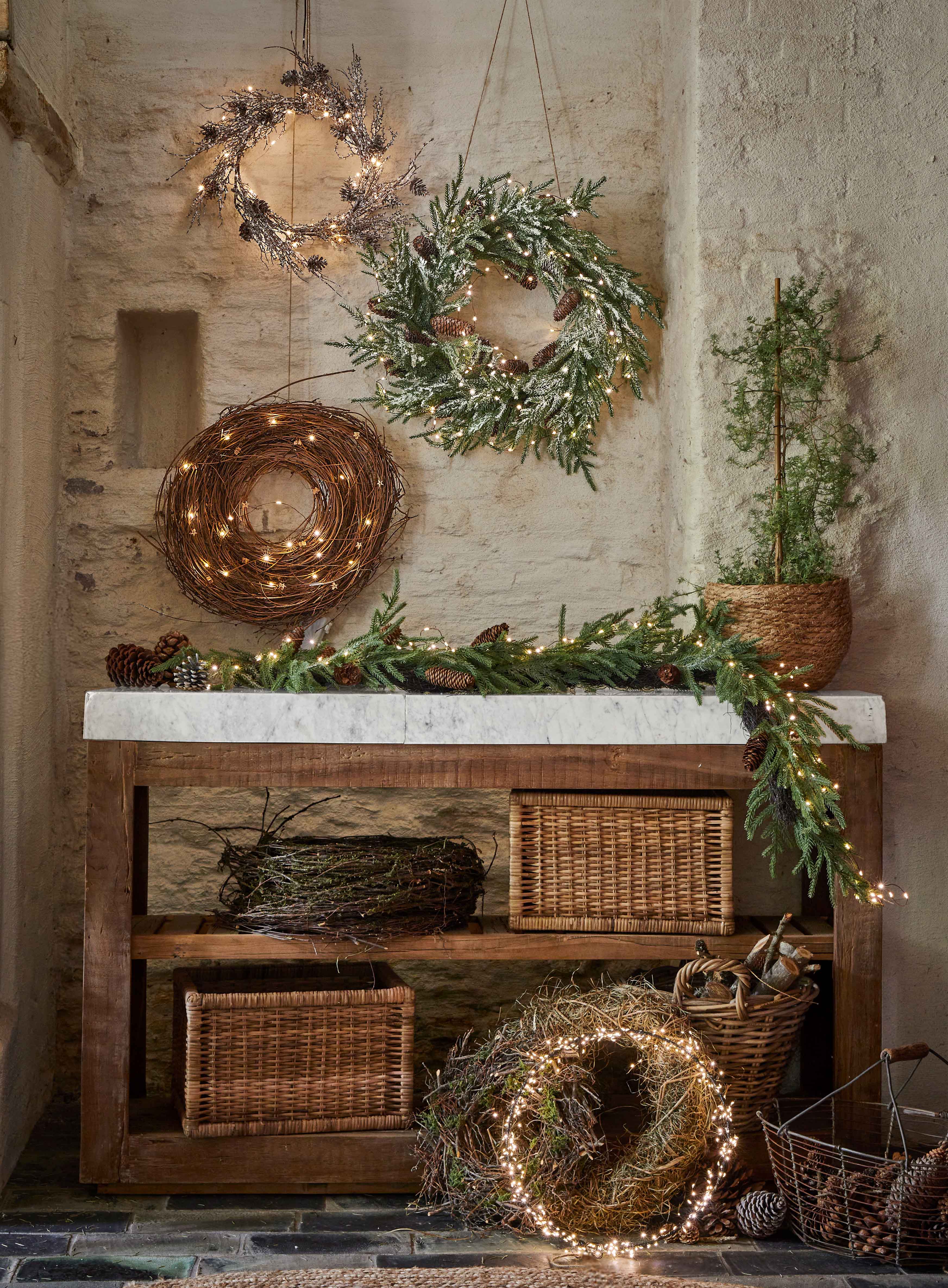 Ghirlande natalizie decorative di rami, pigne e luci su tavolo in legno in ambiente rustico