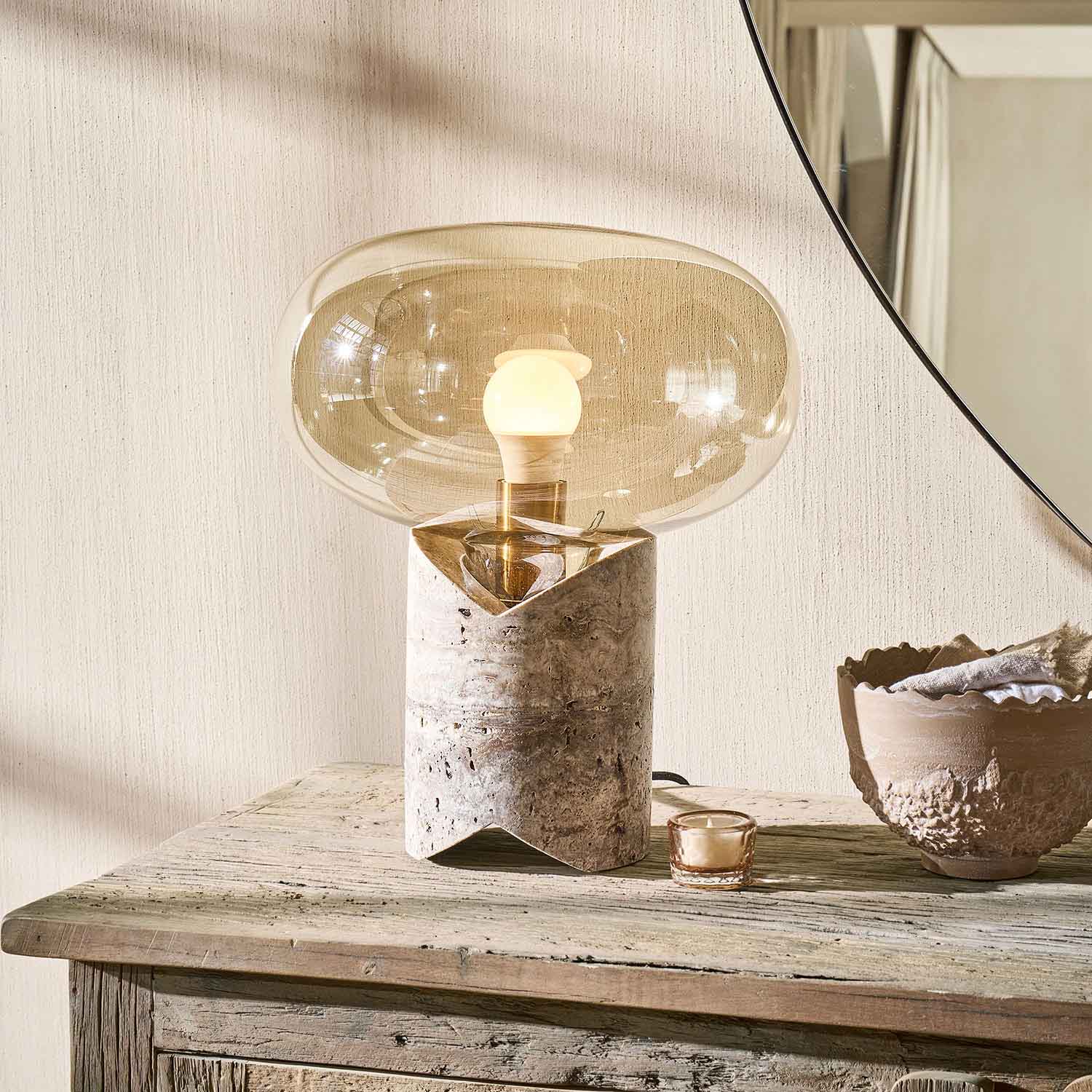 Lampada da tavolo con base in marmo e paralume in vetro trasparente beige su tavolo in legno