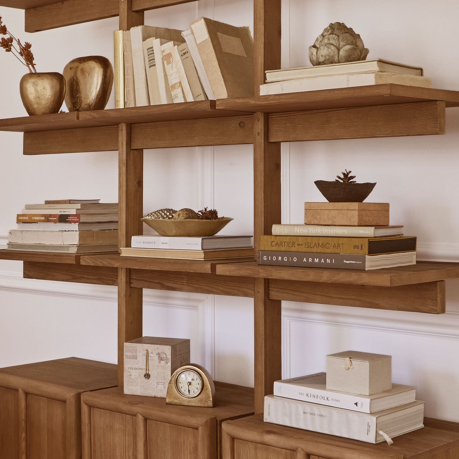 Scaffale in legno con libri, decorazioni dorate e orologio, arredamento elegante per interni