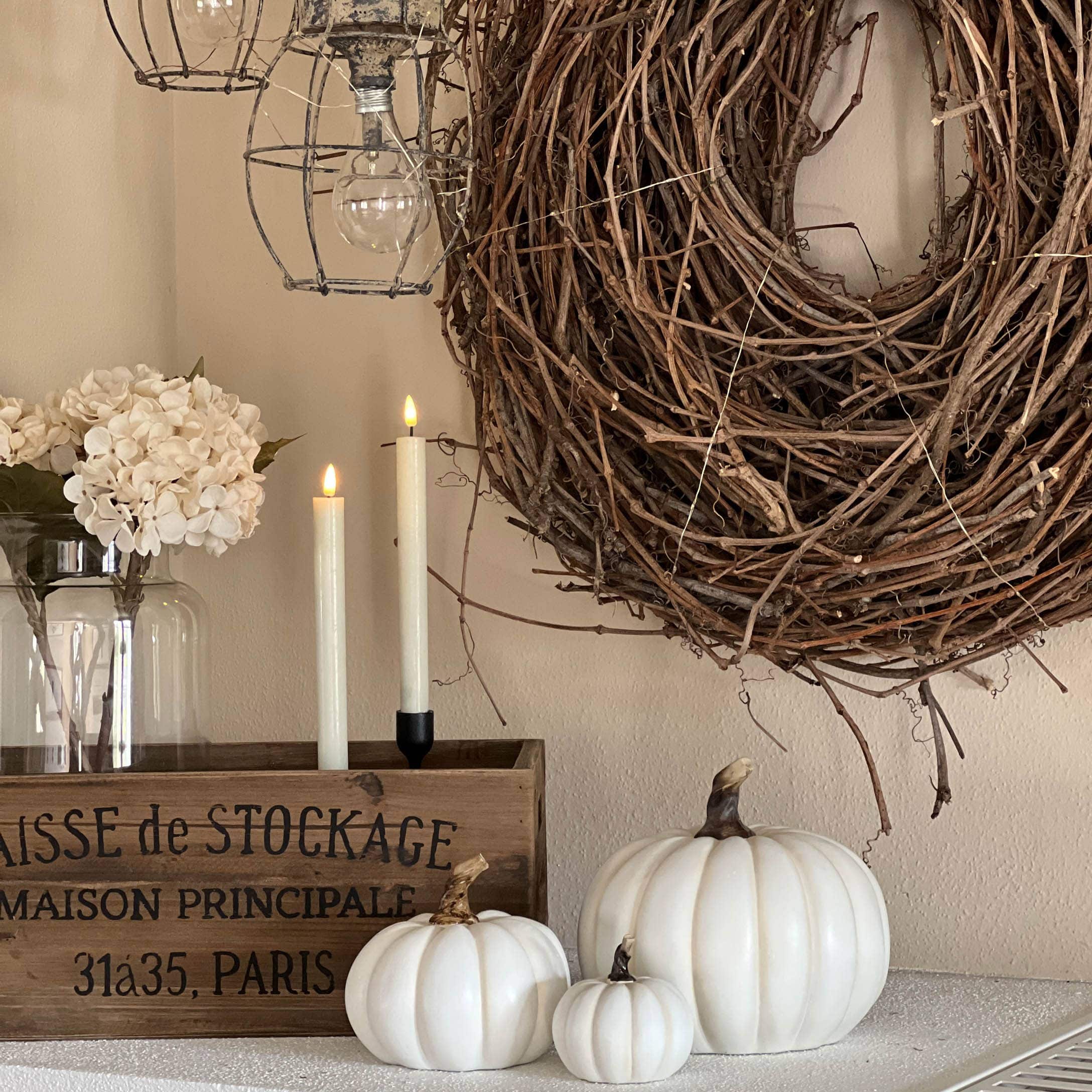 Decorazione autunnale con zucche bianche, cassa in legno e corona naturale di rami per interni