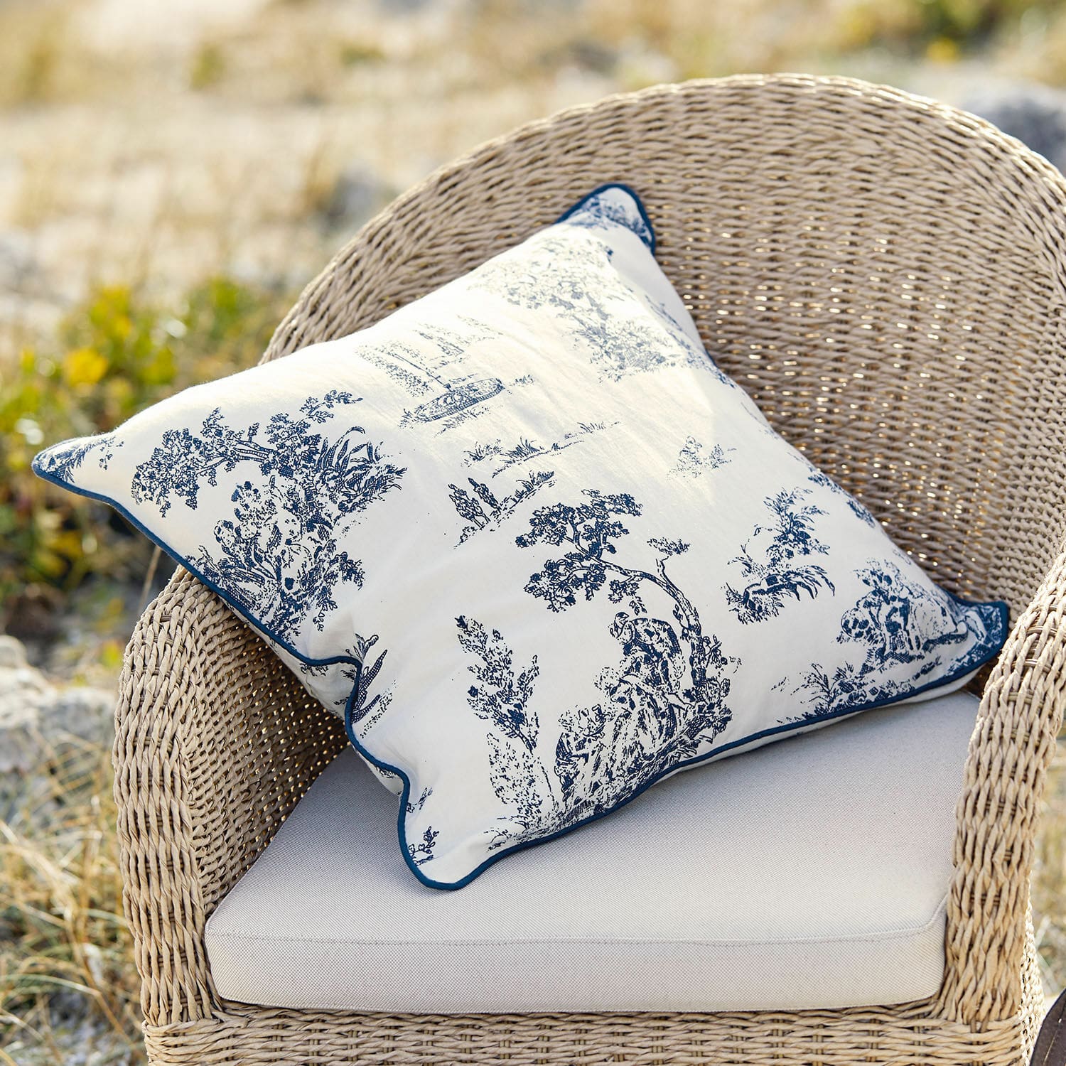 Copricuscino Simone Cuscino decorativo in cotone bianco con motivo classico blu su sedia in vimini
