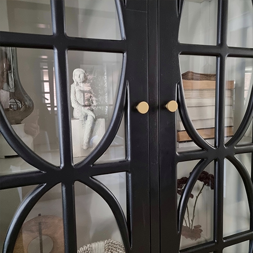 Mobile nero in metallo con motivo decorativo e ante in vetro, decorazioni visibili all'interno