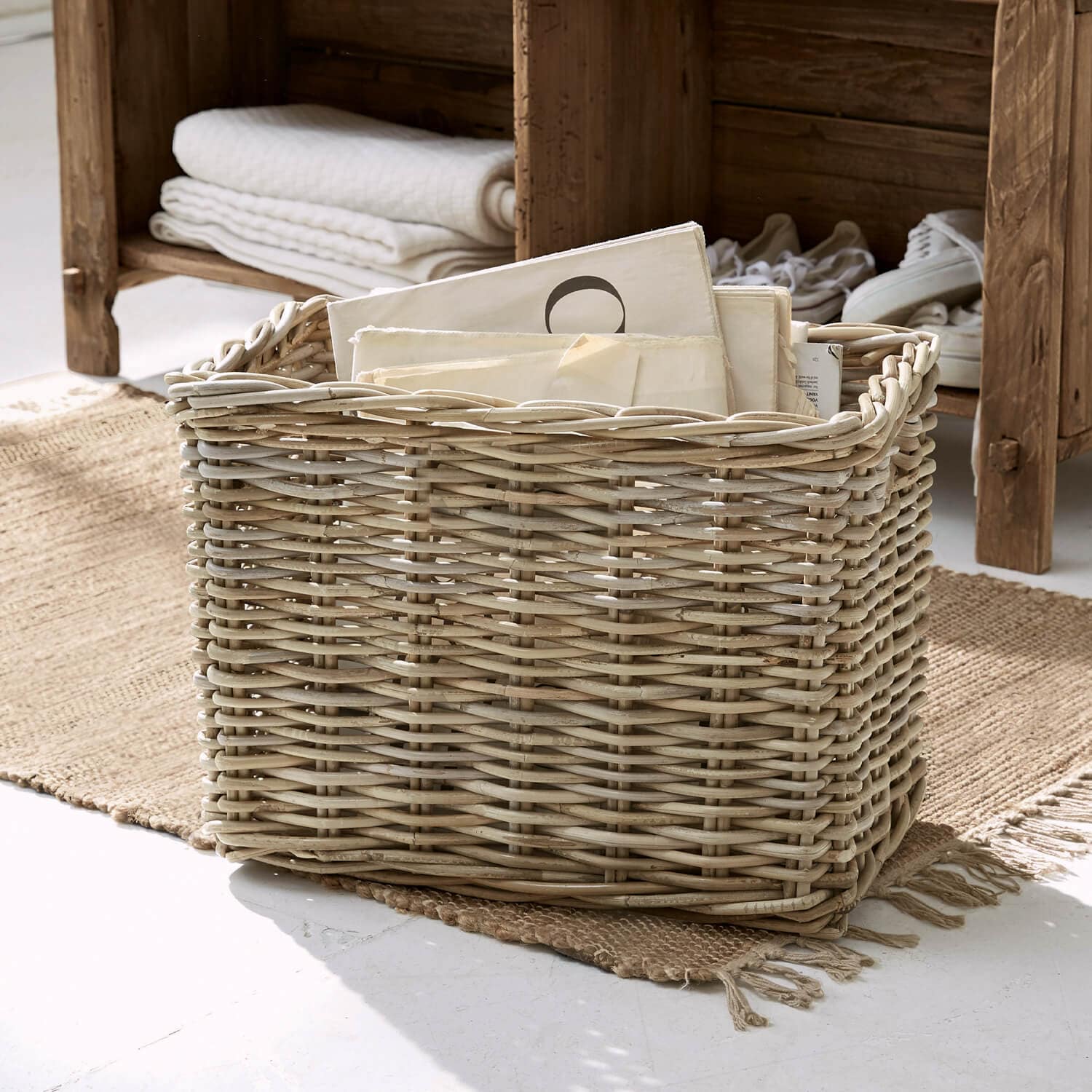 Cesto in vimini naturale con documenti su tappeto in ambiente luminoso, soluzione decorativa e contenitiva