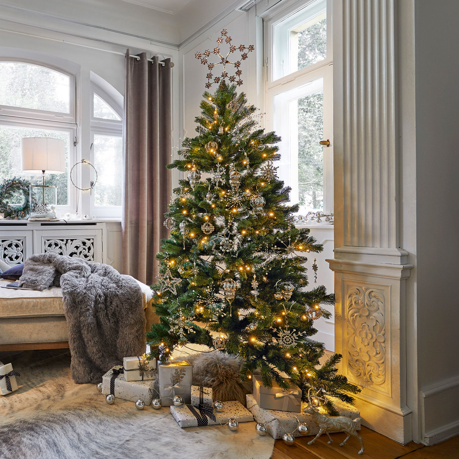Albero di Natale Helford Albero di Natale verde con decorazioni dorate e luci in soggiorno luminoso con regali sotto