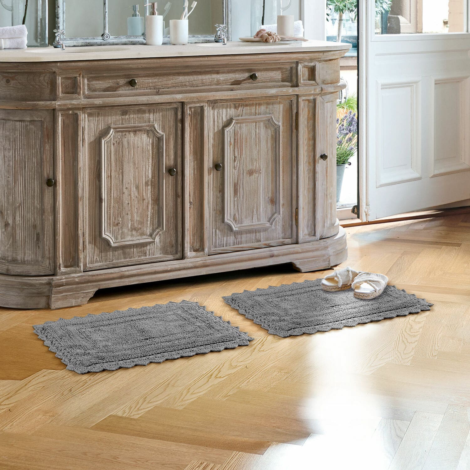 Scendibagno Yalexir Tappeti da bagno grigi in cotone su pavimento in legno chiaro davanti a mobile rustico con lavabo