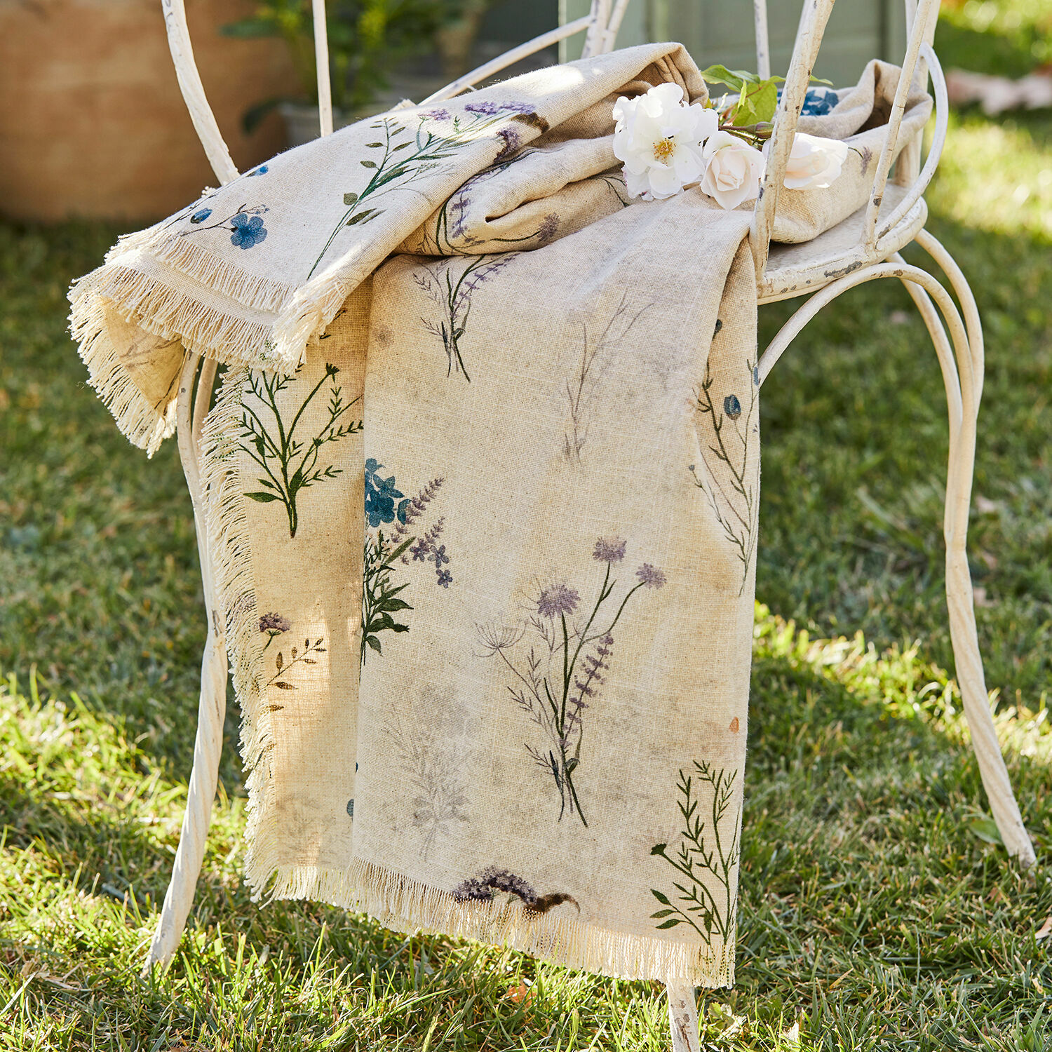 Plaid Cabinda Tovaglia in lino beige con stampa floreale e frange su sedia metallica bianca in giardino