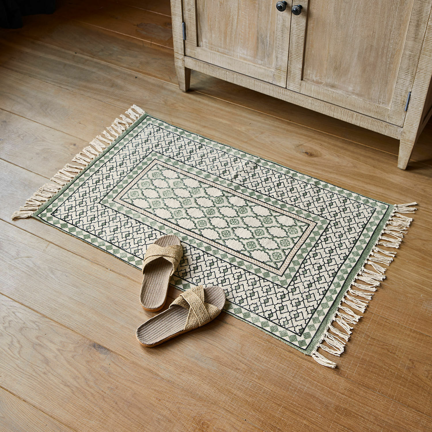 Scendibagno Vellantino Tappeto in cotone verde e crema con frange su pavimento in legno, decorazione d'interni elegante